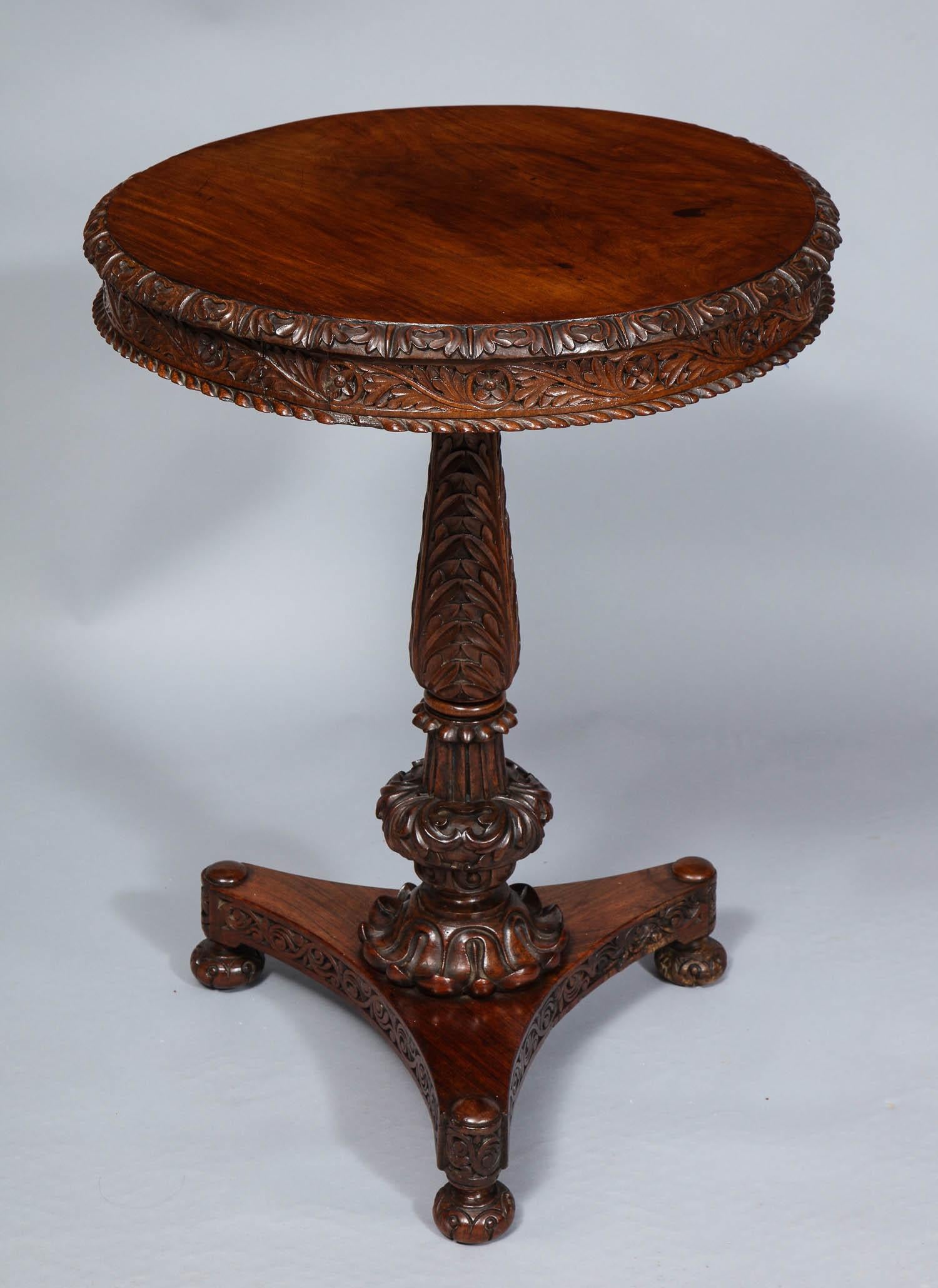 Fine carved padouk round tilt top table with acanthus leaf carved edge and apron over gadrooned molding, standing on turned and carved shaft over three footed platform base, all nicely conceived and executed, circa 1830-1840. Bearing a label from
