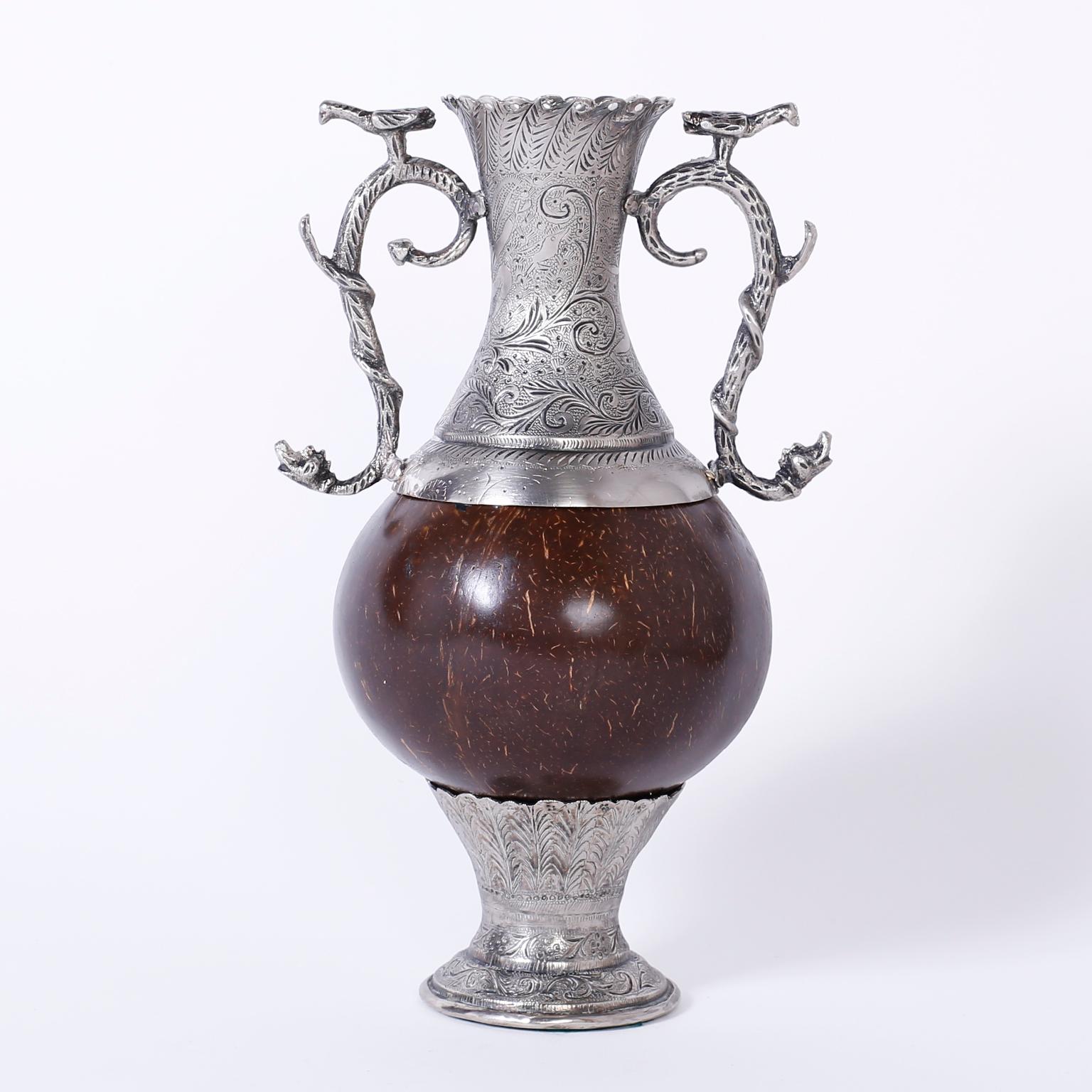 Antique Spanish Colonial vase with an unusual combination of materials. The vase is silvered metal with floral engravings and graceful handles depicting birds on snakes. The center in the Anglo-Indian manner is a polished coconut on a floral