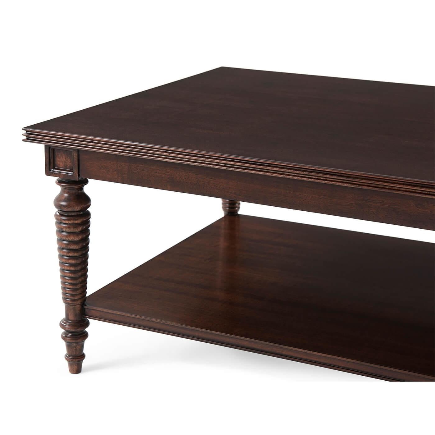 A Regency style, Anglo Indian influenced coffee table with turned and tapering bobbin legs and peg feet, evoking a British West Indies colonial vibe. The rectangular reeded-edge coffee tabletop offers ample surface space, matched with a lower tier