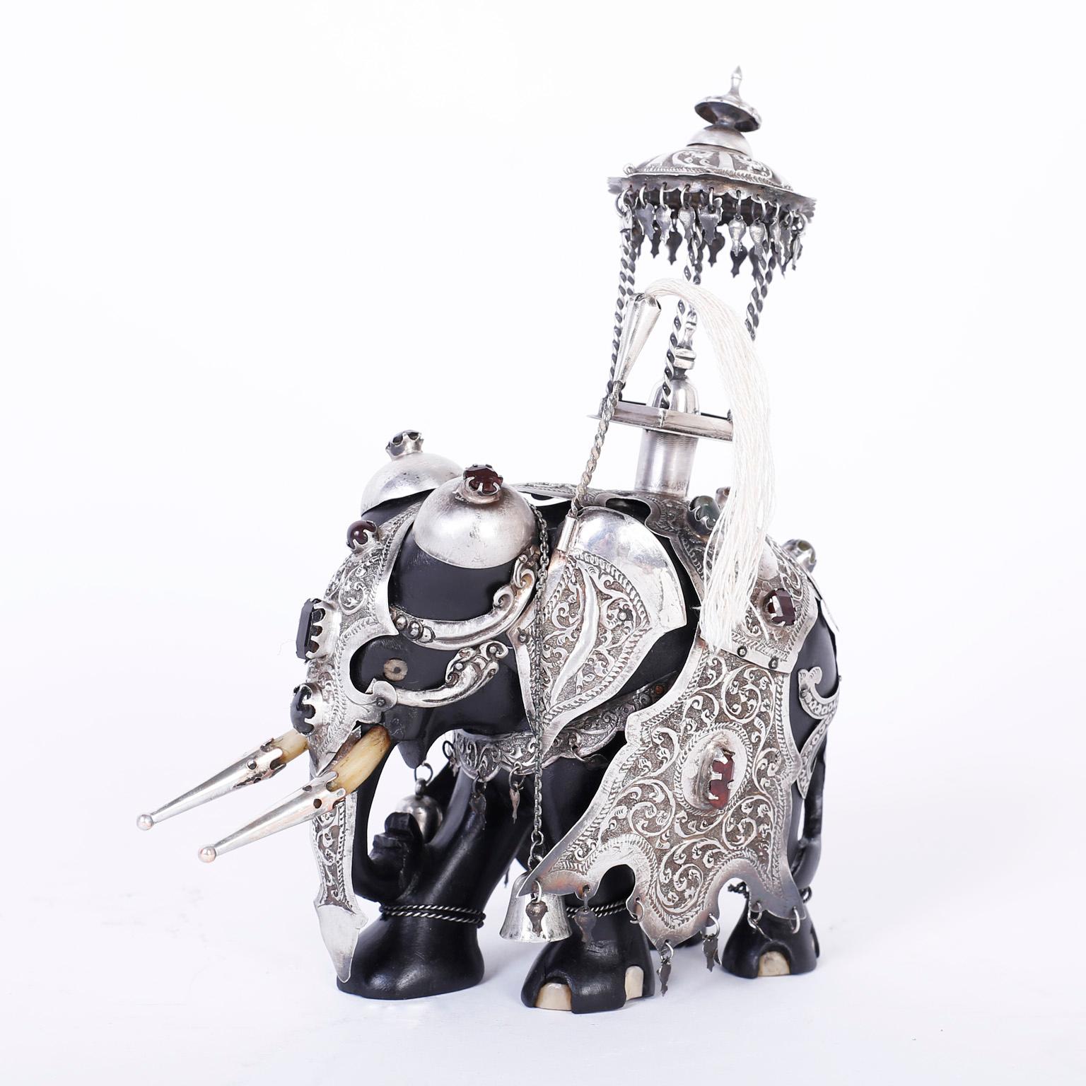 Captivating Anglo-Indian carved ebony elephant elaborately decorated in silvered metal regalia hand engraved with floral designs and highlighted with semi precious stones. Best of the genre.