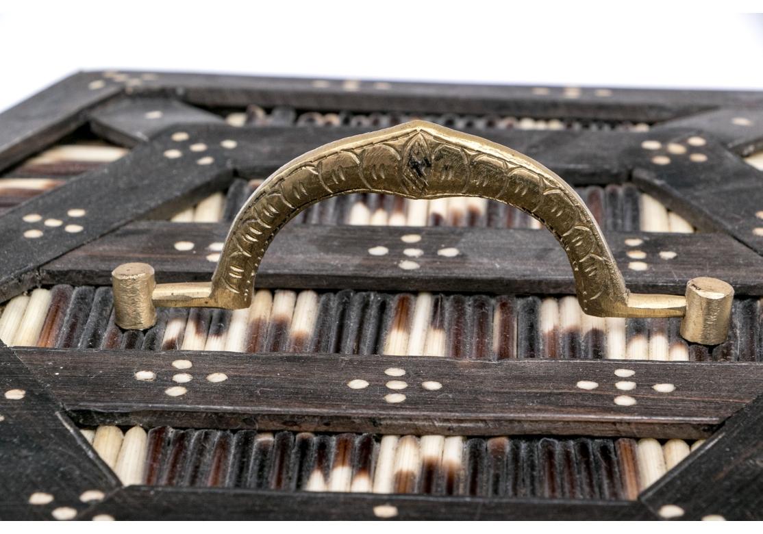 A substantial Anglo-Indian hexagonal porcupine quill box comprised of dark hardwood with inlaid bone dots framing the regimented panels of porcupine quills. The box with a central brass handle opens to reveal an embossed red velvet lining and 7