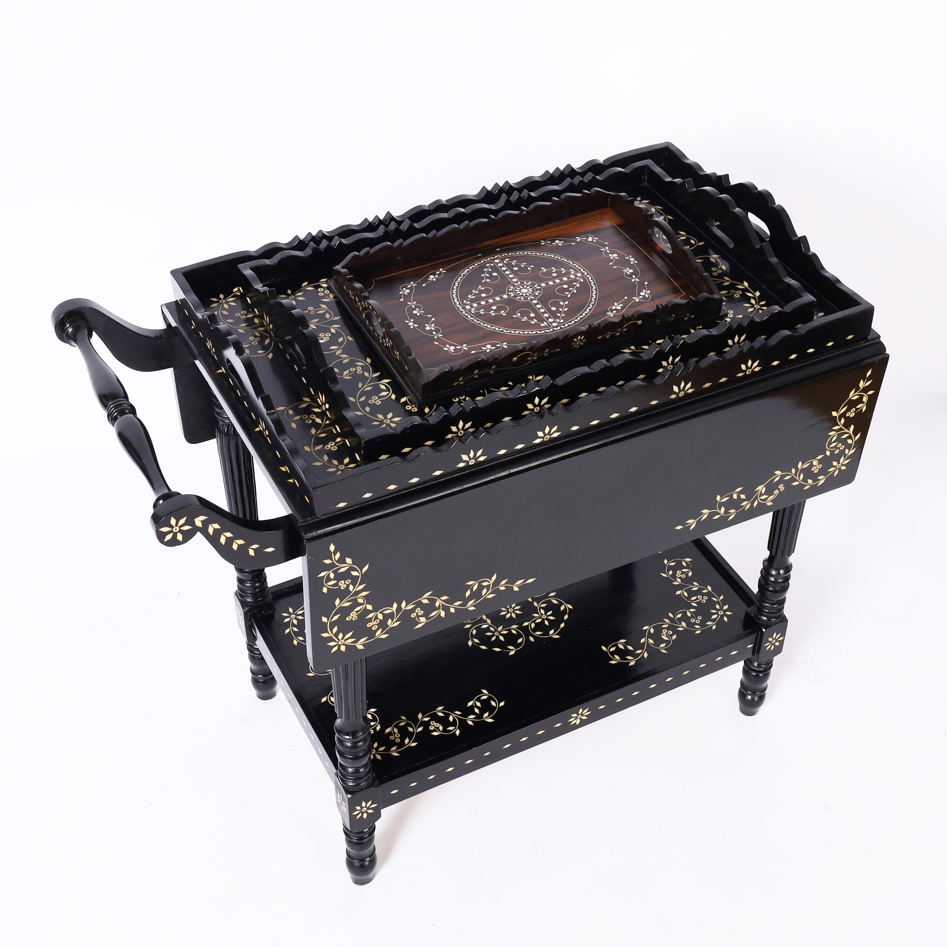 Standout vintage Anglo Indian server or bar crafted in indigenous hardwood with an ebonized finish featuring drop leaves, turned legs, three trays and floral bone inlays throughout. 

Closed depth is 18