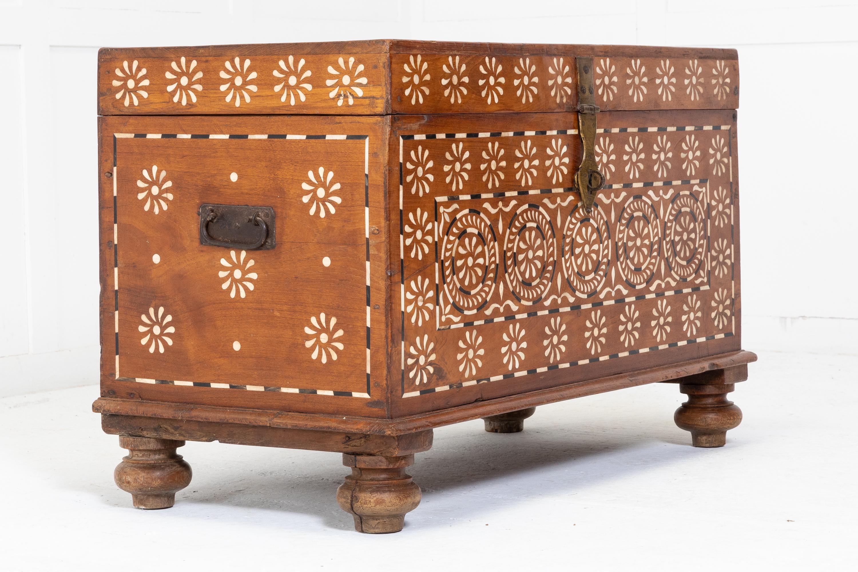 A wonderfully decorated, Anglo Indian bone inlaid teak trunk. A good size with intricately decorated inlaid circles. Having brass carrying side handles and brass front lock. Standing on plinths and turned bun feet. Circa 1920.

A very decorative