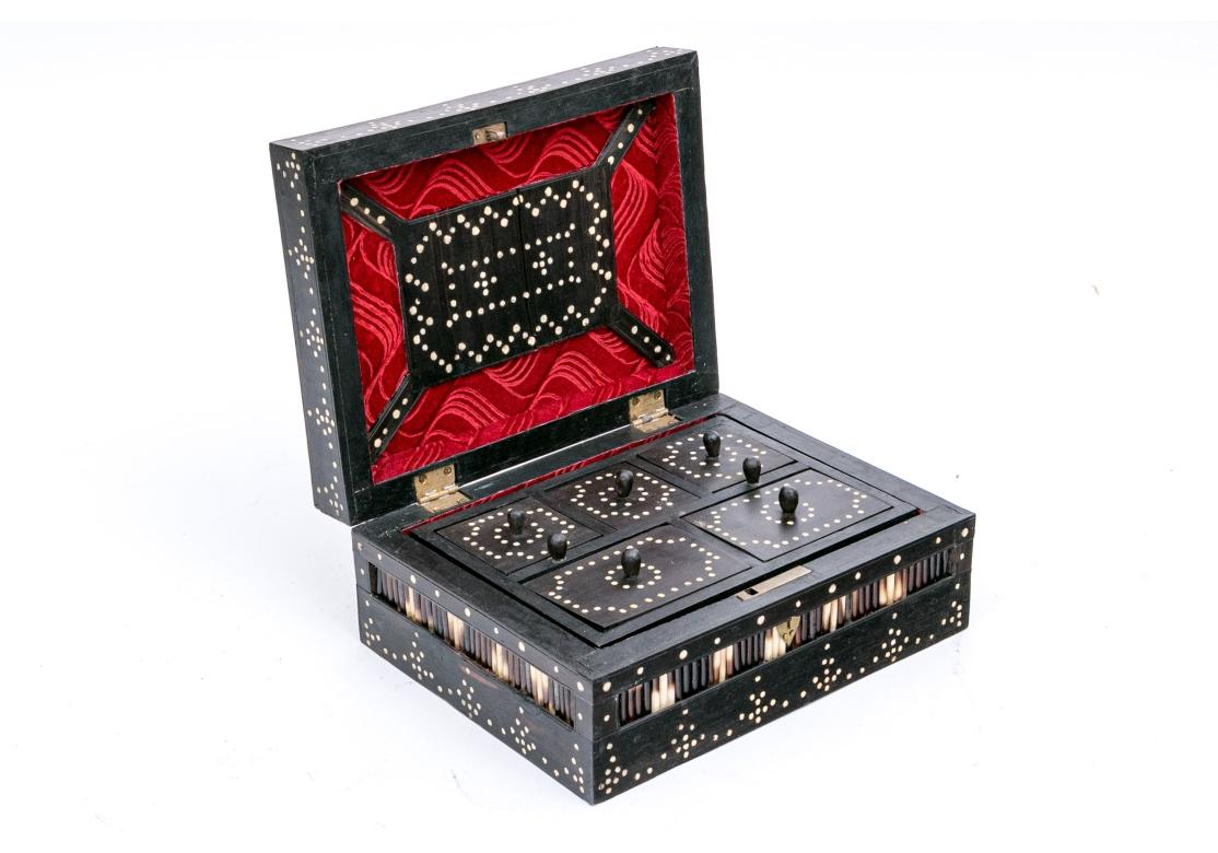 A substantial Anglo-Indian rectangular porcupine quill box comprised of dark hardwood with inlaid bone dots framing the regimented panels of porcupine quills with a central brass handle. The box opens to reveal an embossed red velvet lining and 5