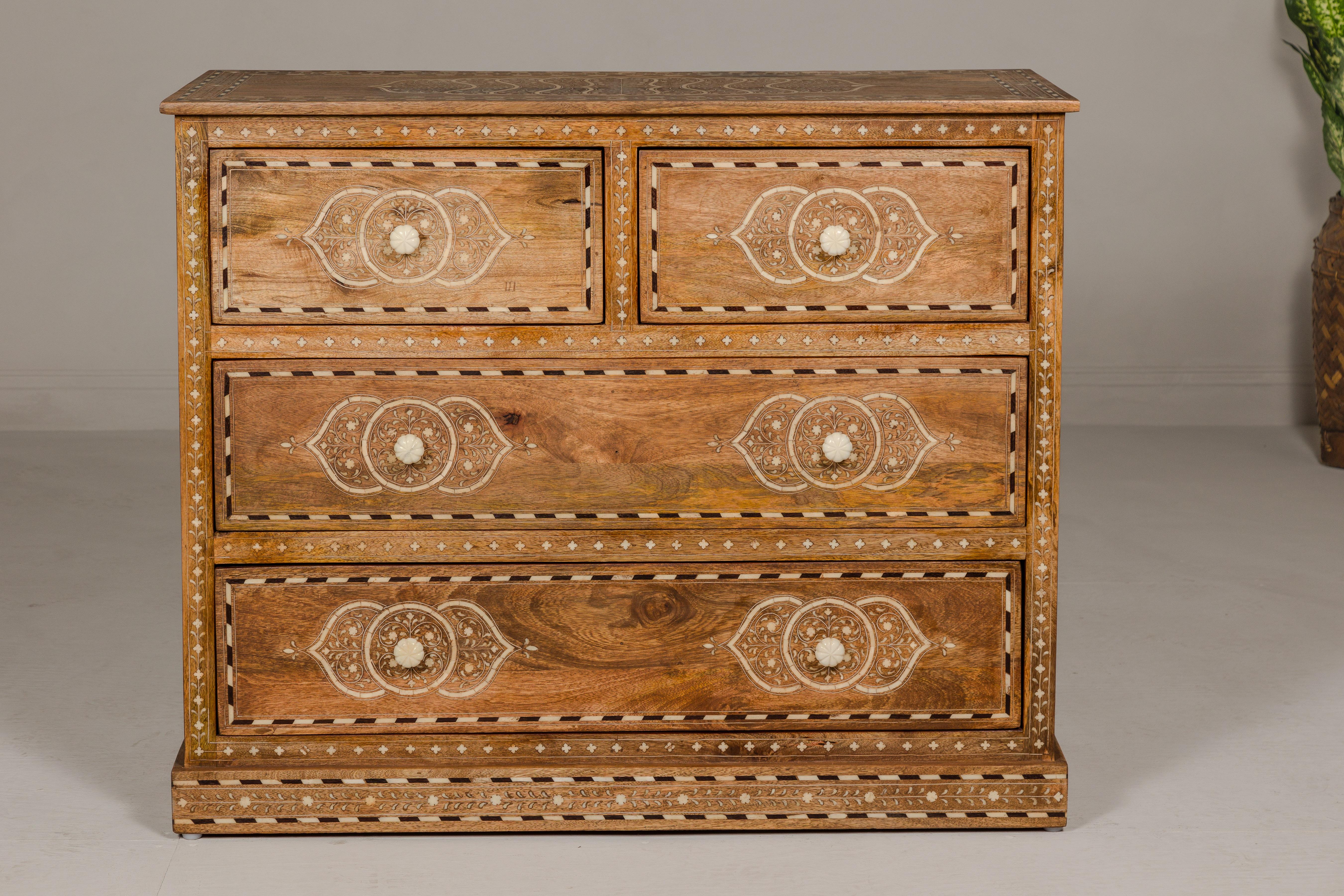 An Anglo Indian style mango wood chest with four drawers, floral themed bone inlay and bone hardware. Immerse your home in the vibrant artistry and rich heritage of Anglo-Indian craftsmanship with this exquisite mango wood chest, adorned with