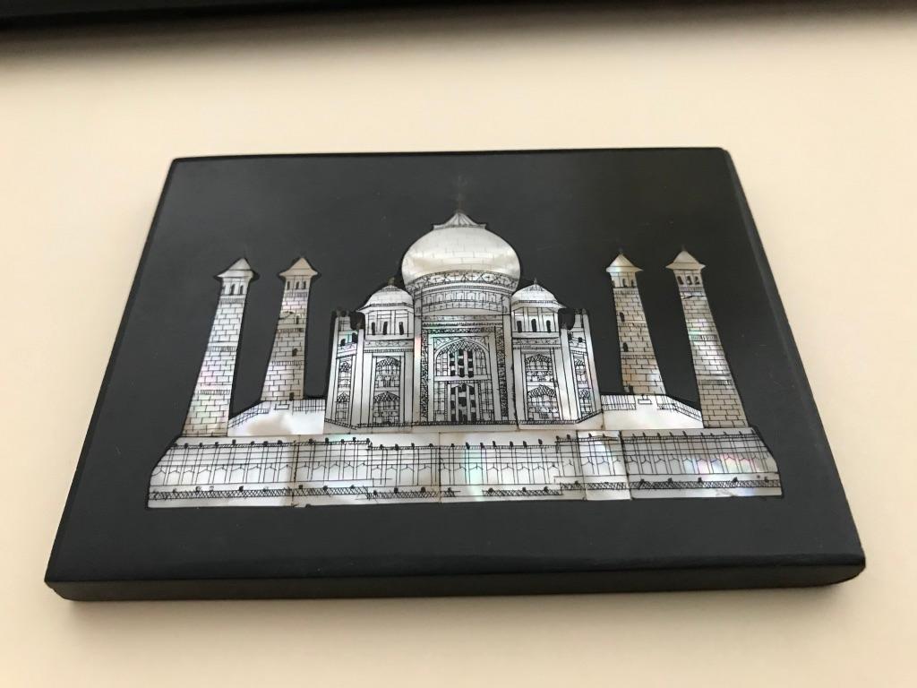 Black marble paperweight with an inlaid image of the Taj Mahal in mother of pearl. This unusual piece has the details drawn on the mother of pearl in black ink, giving it the appearance of a micro mosaic. Old paper label marked Agra, India on the