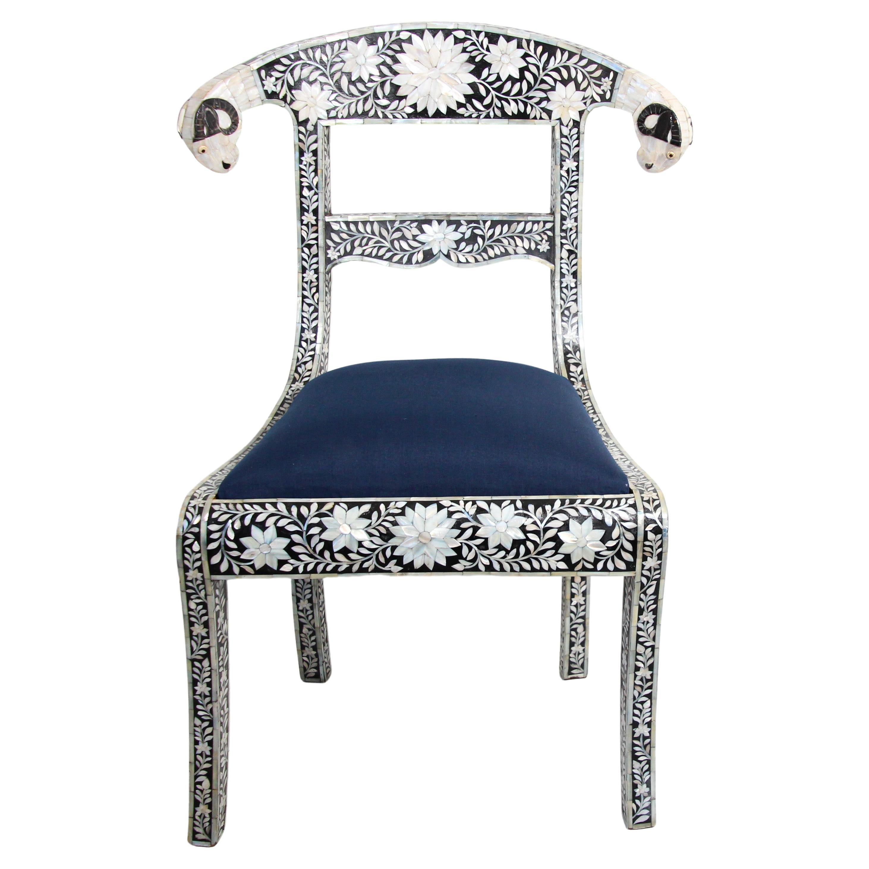 Anglo-Indian Mughal black and white mother of pearl inlaid dining chair with ram head detail.
Mother-of-pearl Klismos style chair, this stunning chair feature a wooden frame inlaid with intricate and detailed floral design in white mother of pearl