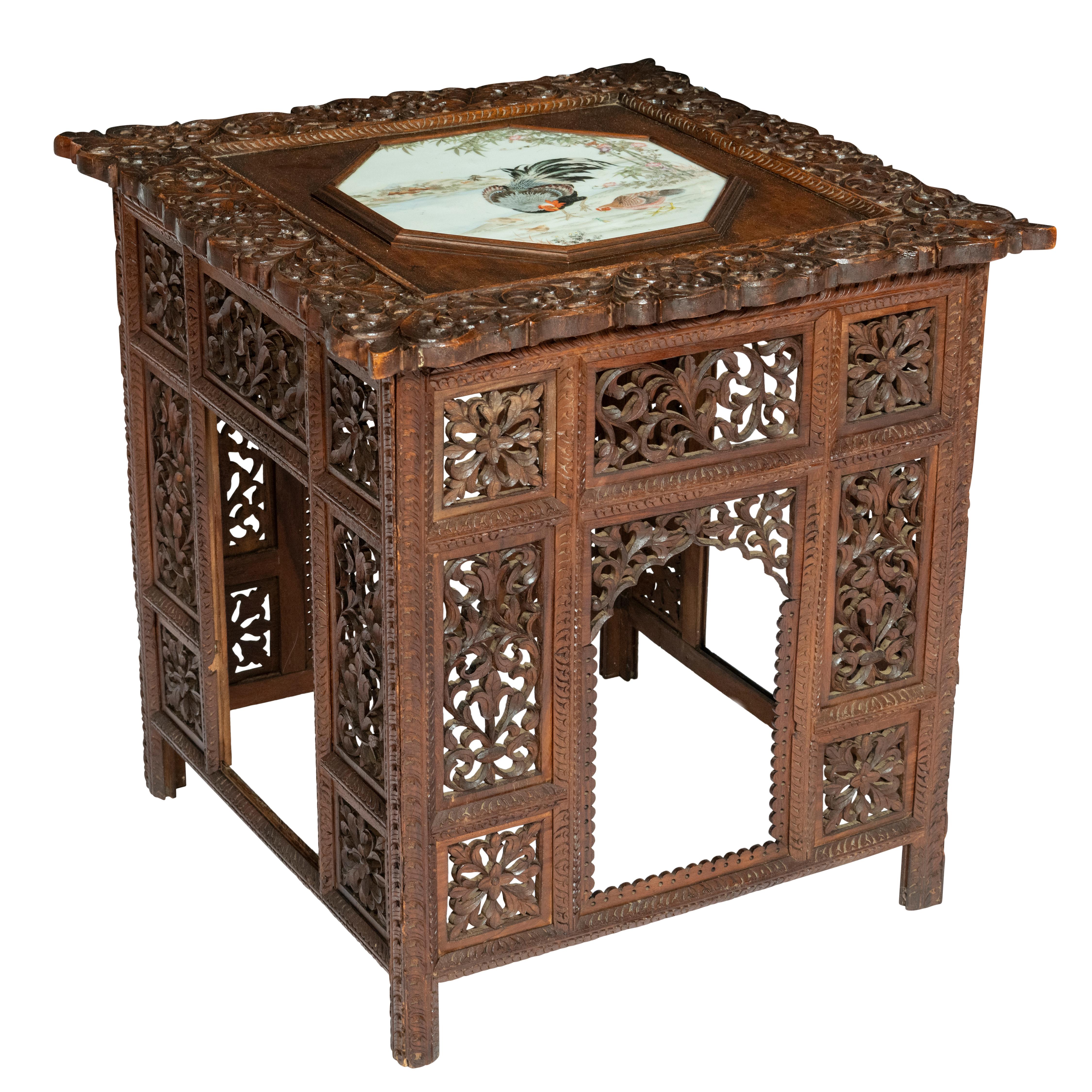 A large unusual Anglo-Indian Occasional Table. Square form

Indian Teak. The top set with an early Chinese 18th painted porcelain panel depicting rare exotic birds, famille rose.

Profusely carved with Leaves, flora and scrollwork

India, circa 1890