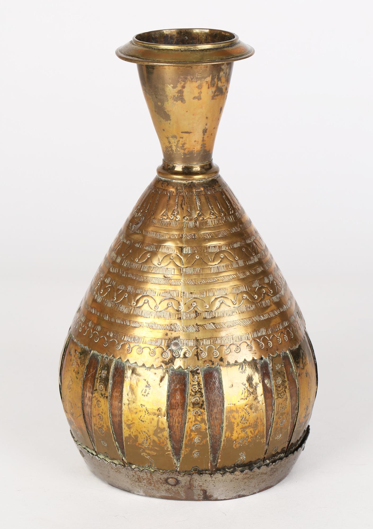 A stytlish antique Indian or Middle Eastern coconut vase overlaid and mounted with brass dating from the 19th century. The vase has a coconut body with an inset turned wood base and is mounted with a brass upper body applied with incised patterning,