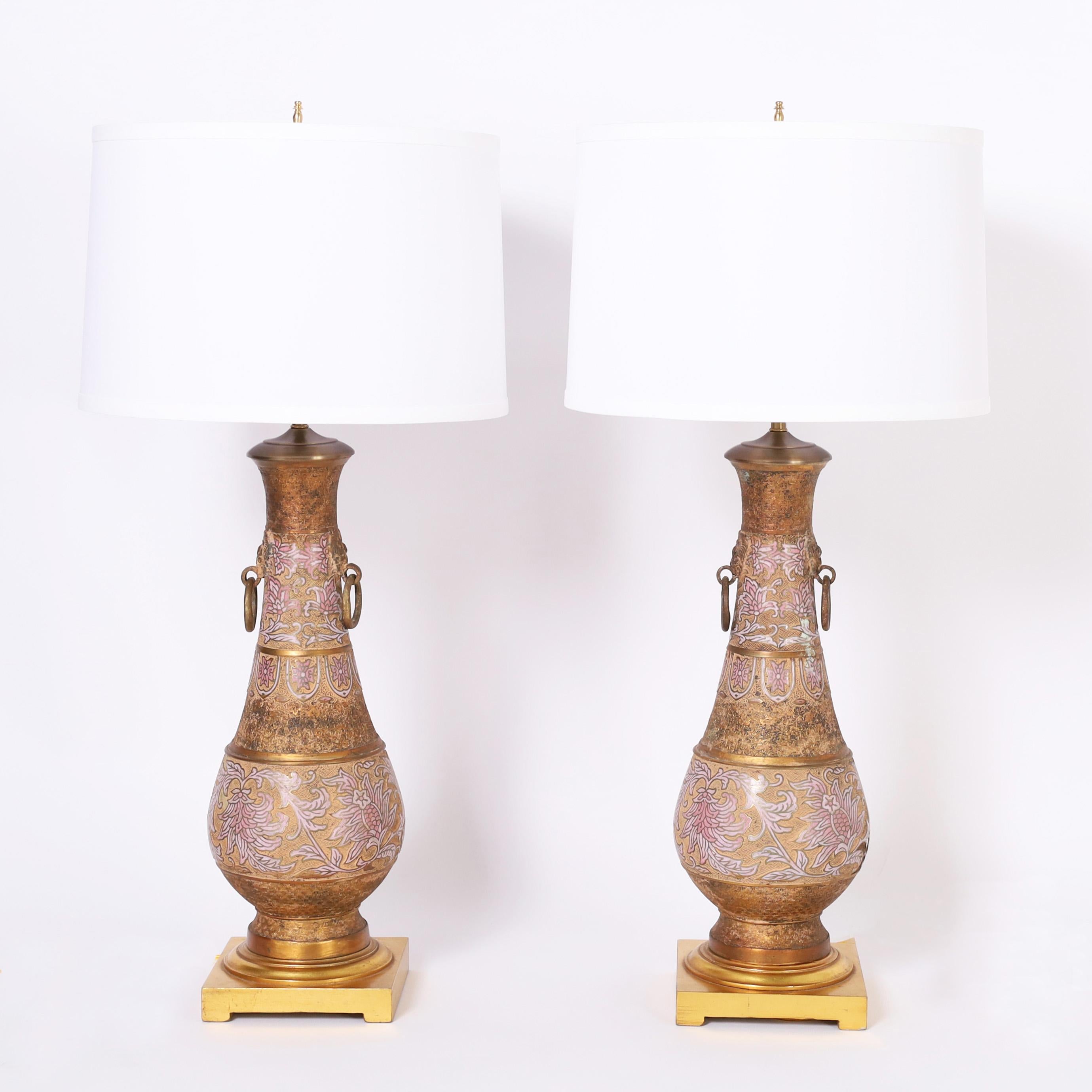 Vintage pair of Anglo Indian table lamps crafted in cast brass with engraved geometric and floral designs decorated with lovely pastel enamel highlights. Presented on gilt wood bases.