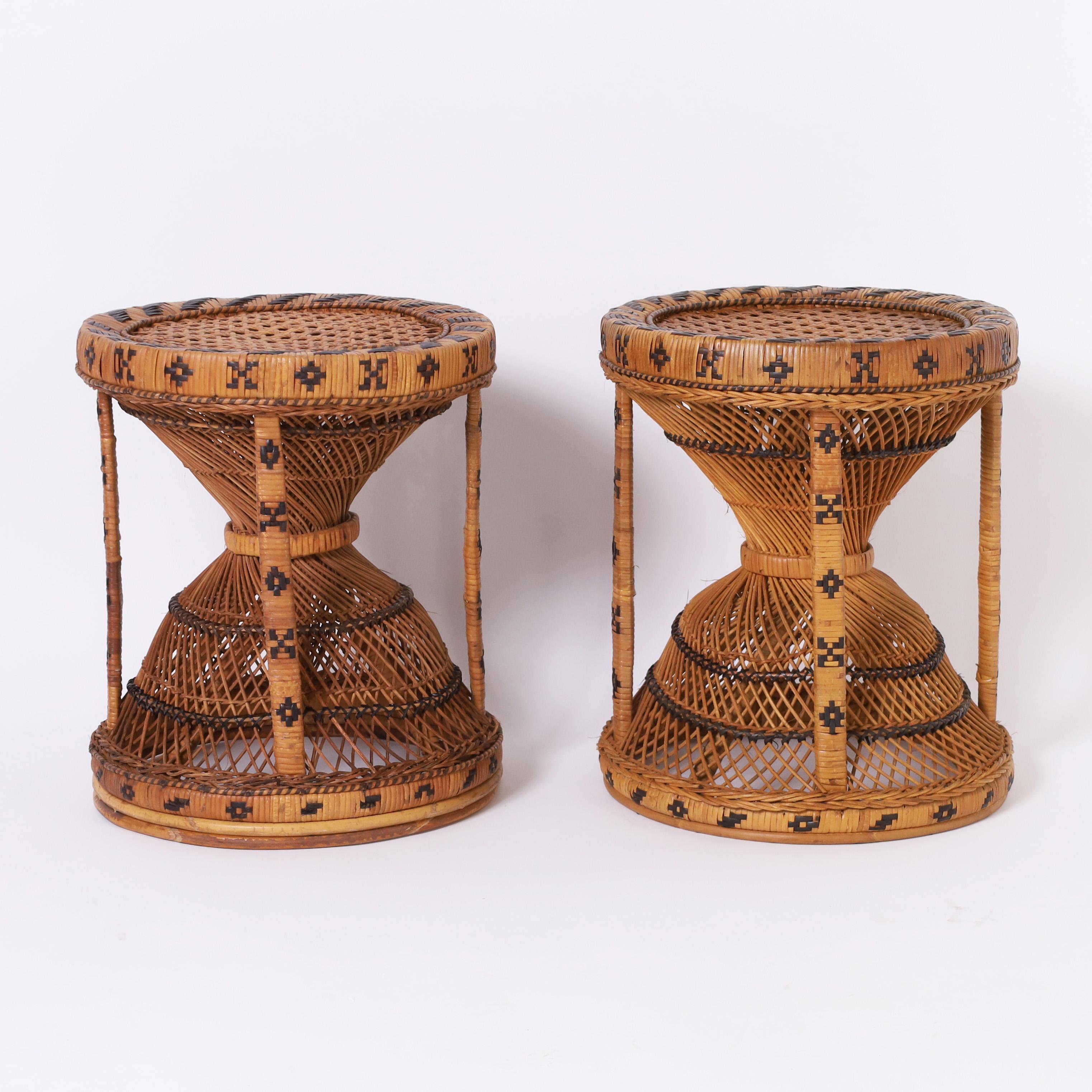 British colonial pair of Anglo Indian stools or stands handcrafted in wicker and rattan in classic hourglass form with caned tops and decorated with geometric symbolic designs.