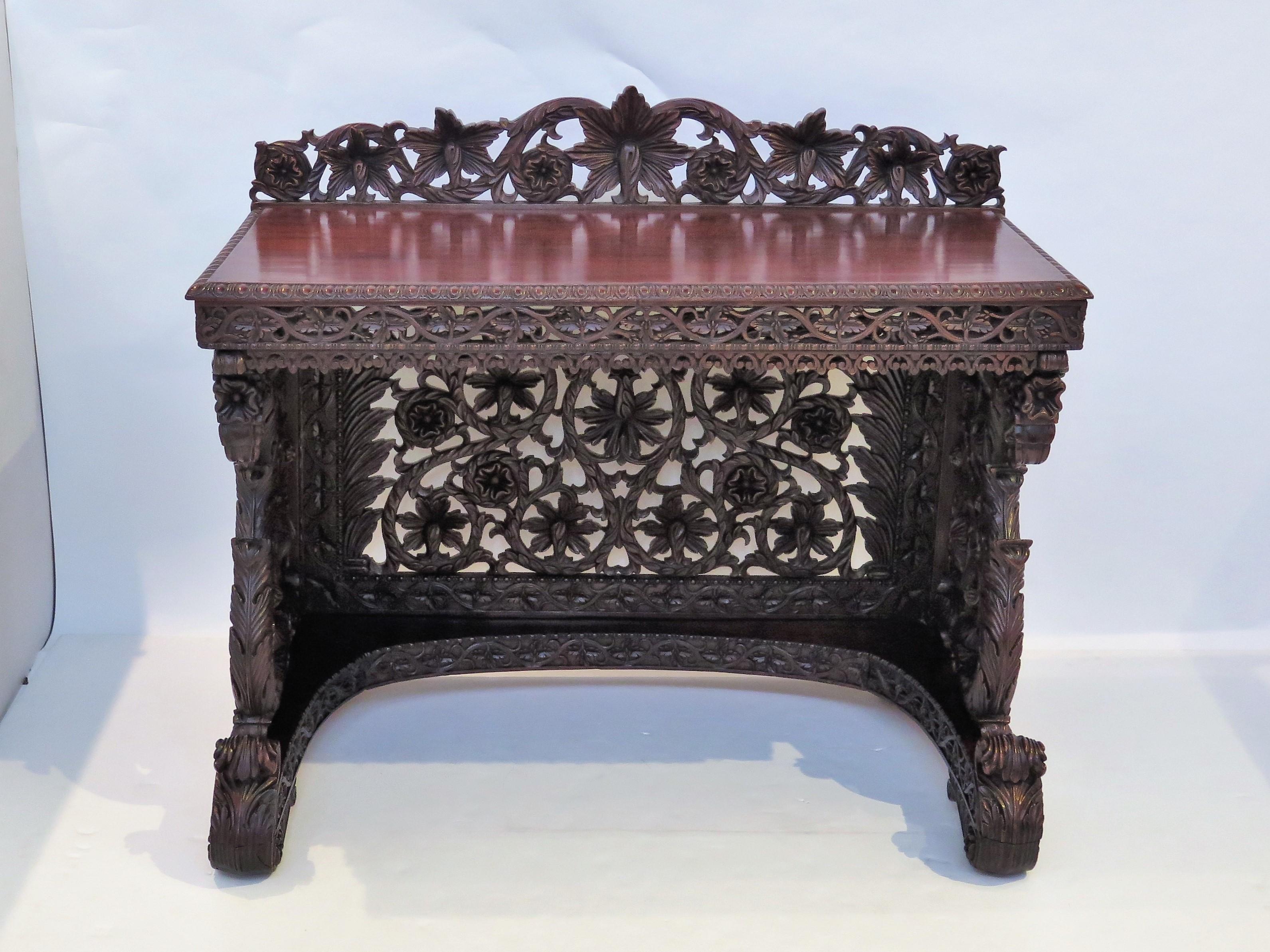 An intricately carved and pierced Anglo-Indian sideboard in rosewood with ornate openwork in an over-all floral design and scrolling acanthus leaves. Solid top and carved back, apron and sides. A carved shelf at the bottom.