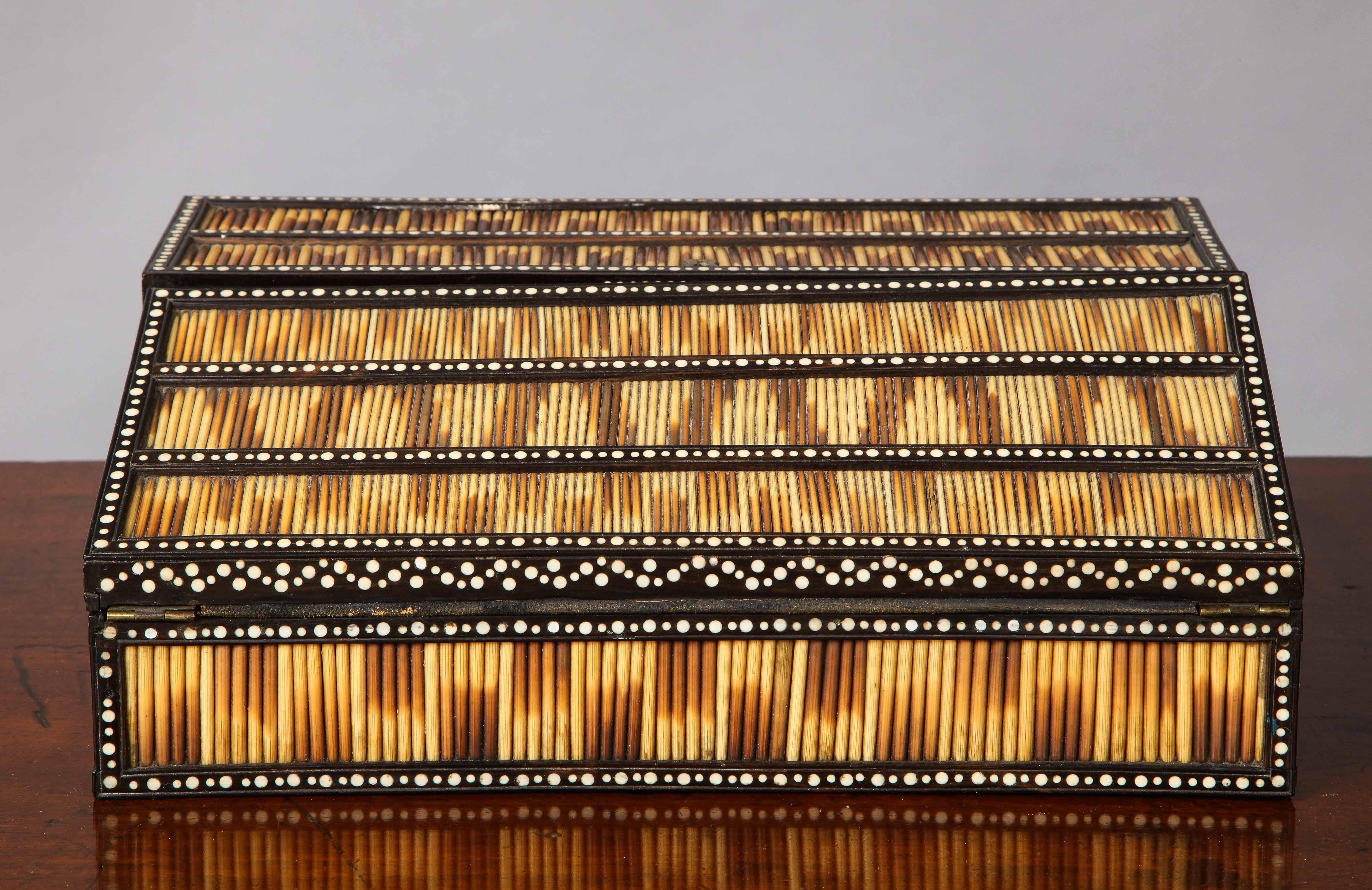 Good mid-19th century porcupine quill decorated writing slope, having bands of striated quills between bone inlaid ebony stiles, the interior finely inlaid with penwork decorated bone flowering urns and elephant, over two inkwells and pen trya, over