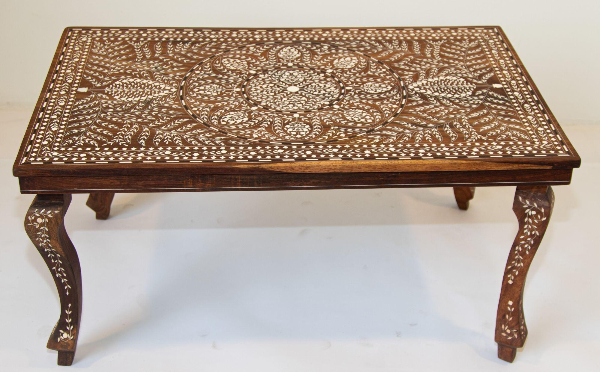 Anglo Indian rectangular coffee table heavily with bone inlay circa 1940's.
This beautiful Mughal Raj table features a top with spectacular foliage hand inlay stylized floral medallion surrounded foliate Moorish designs with a warm brown walnut