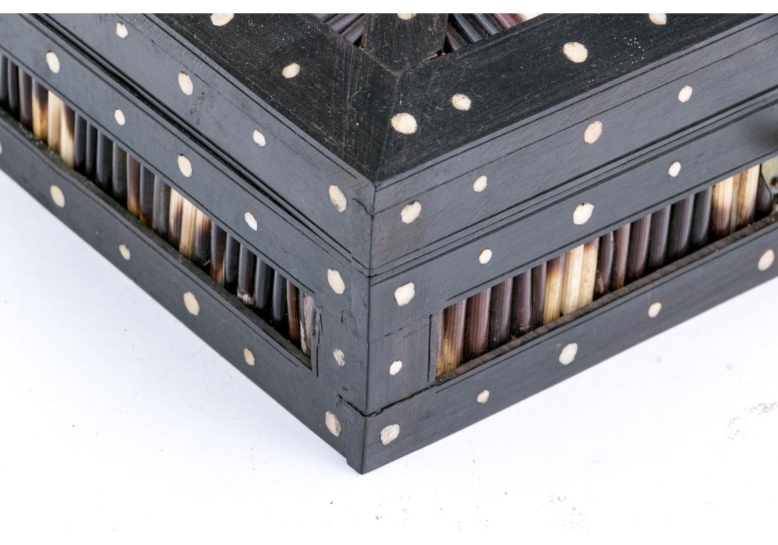 Anglo Indian rectangular porcupine quill, bone and parquetry box. The box with a hinged lid that opens to reveal embossed red velvet lining and a decorated wood panel. The box made of dark hardwood inlaid with bone dots is veneered with regimented