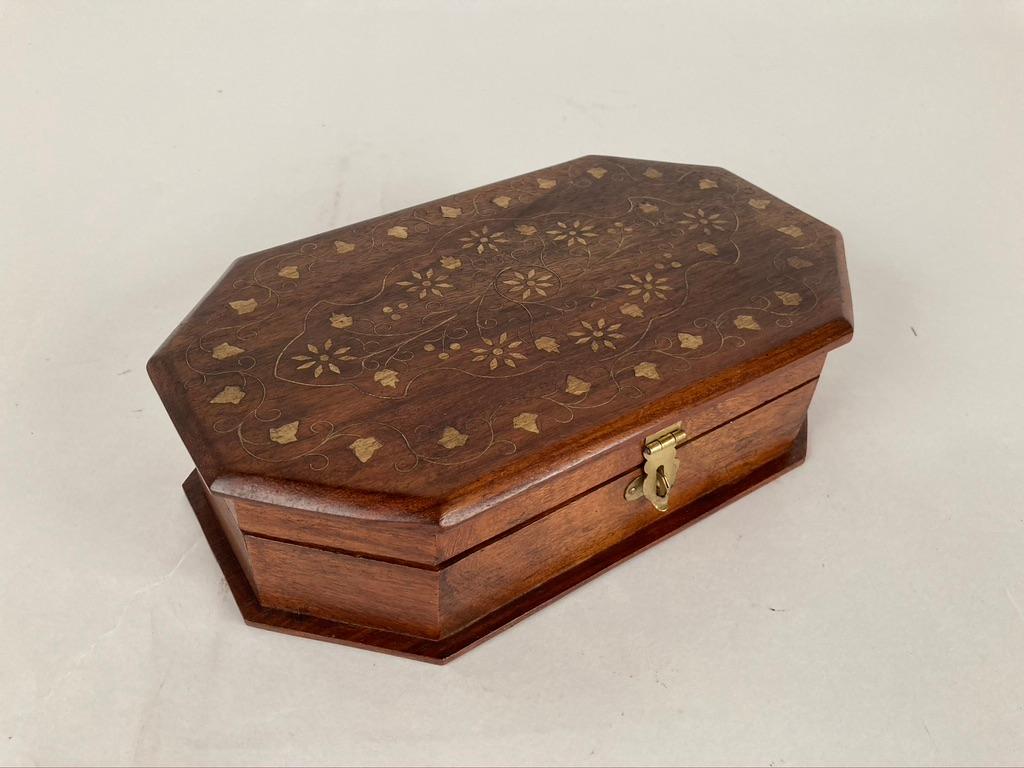 An octagonal form hand carved rosewood box with the top inlaid with brass in a floral design. Elegant eight sided form accents the grain of the rosewood.