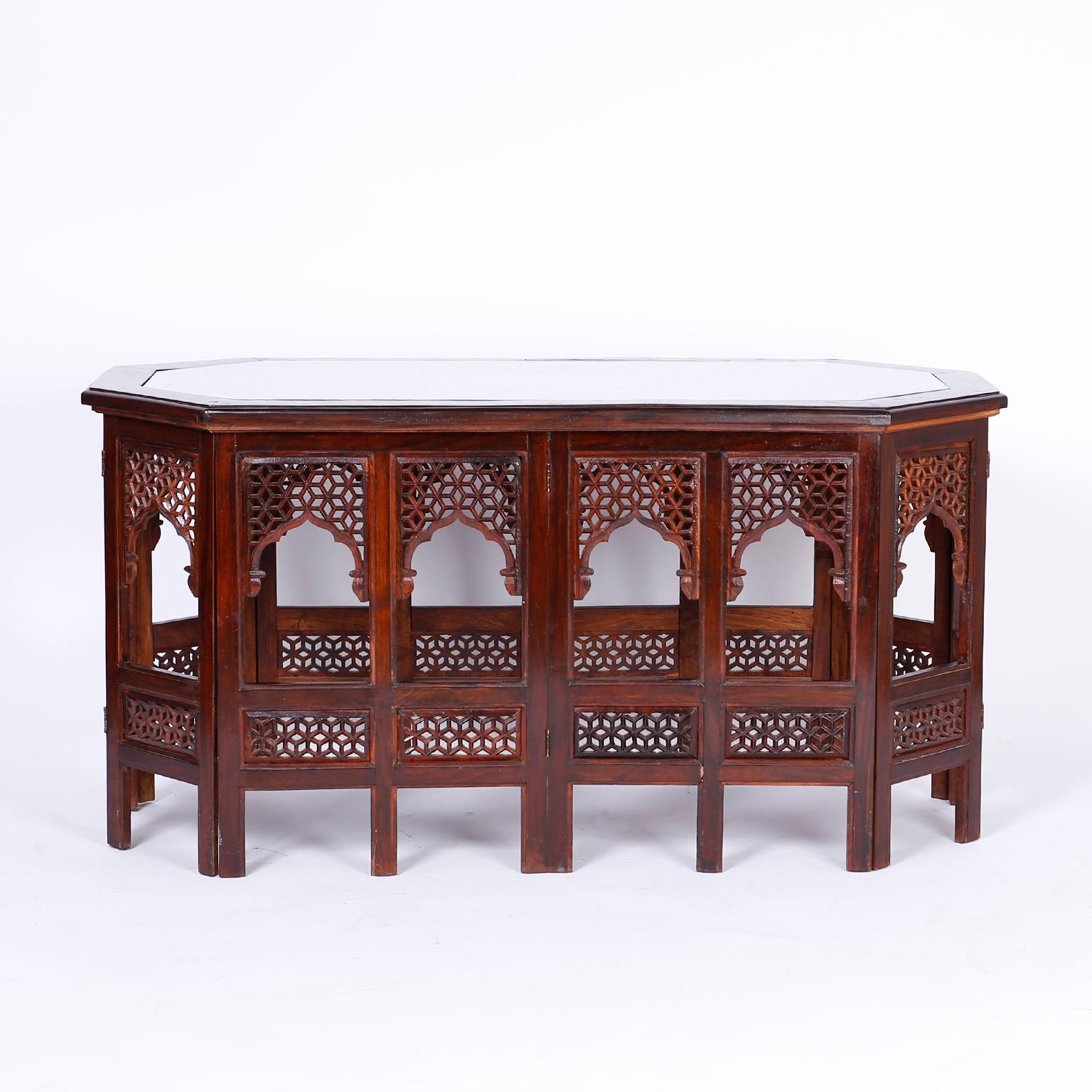 Antique Anglo Indian coffee table crafted in rosewood with a stylized octagon form featuring a carved open fretwork honeycomb top with an oval medallion inlaid with copper and brass and a brass inlaid border. The base has fourteen legs separated by