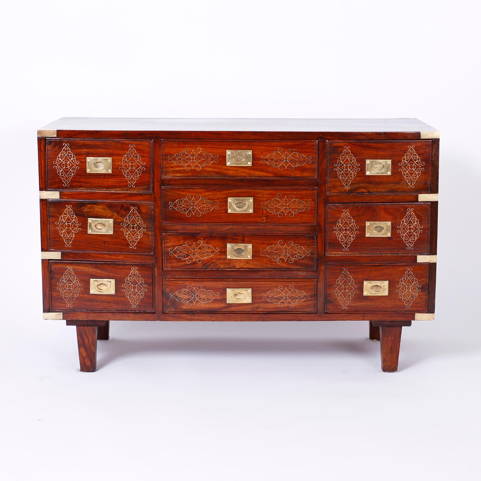 Anglo-Indian chest expertly crafted in rosewood with ten drawers and featuring symbolic floral brass string inlays on the top, drawer fronts and sides, campaign hardware and tapered legs. As seen in the last photo of the listing, a similar chest is