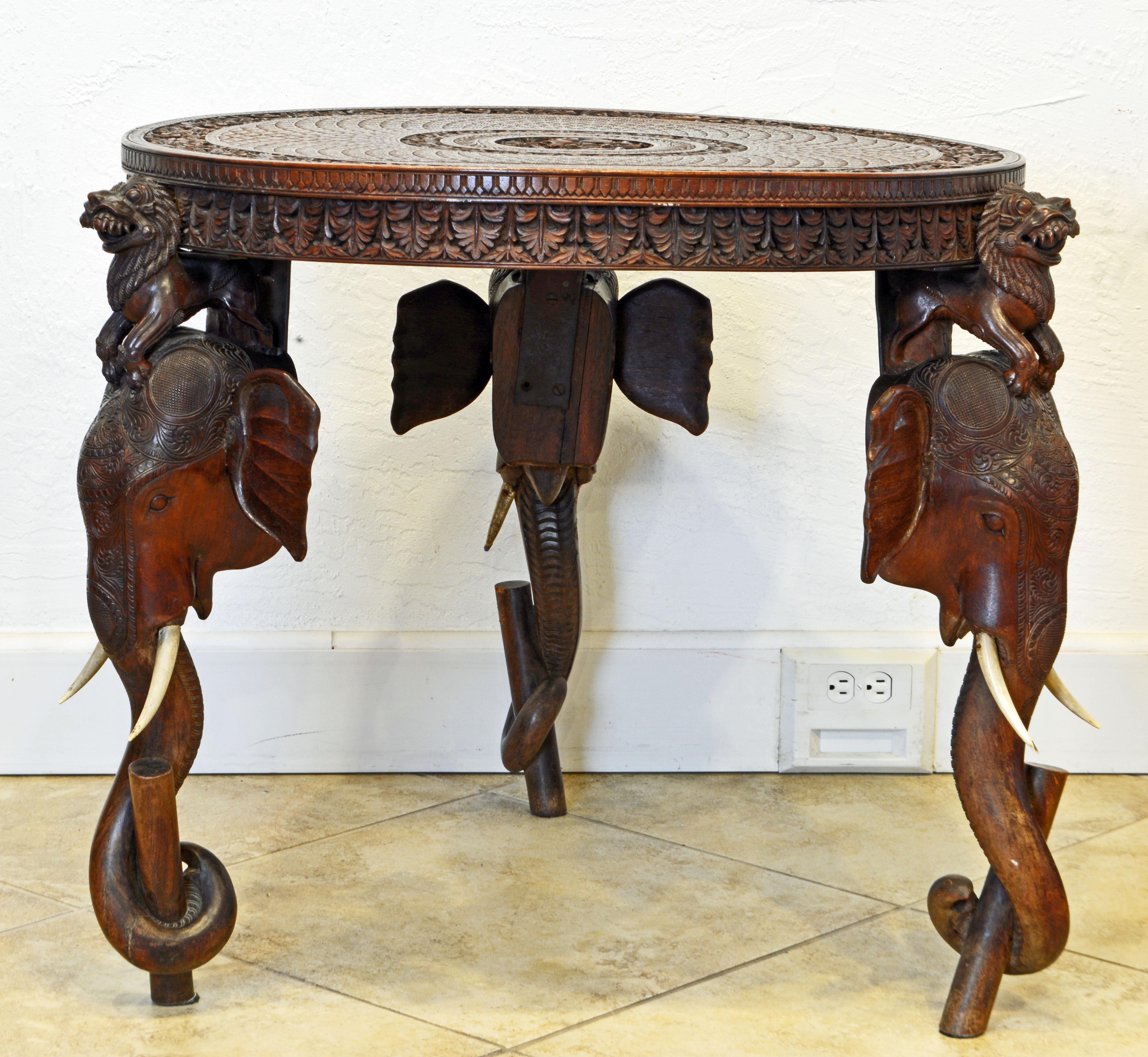 This late 19th century Anglo-Indian side table features an intricately carved apron and top centering a Hindu goddess flanked by two elephants supported by three legs with carved lions sitting on elephant heads with faux tusks and wide spread ears.