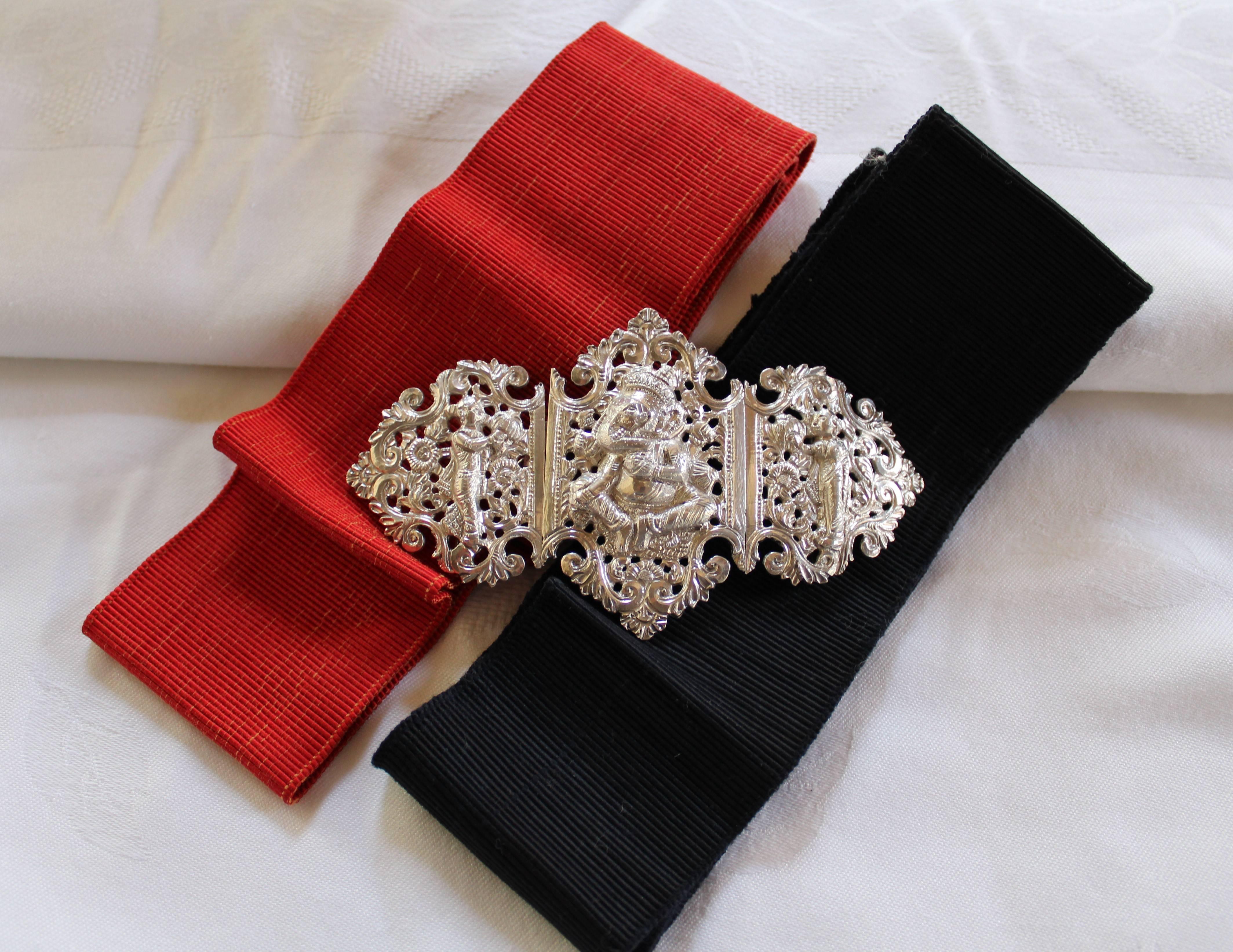 Il s'agit d'une ancienne boucle de ceinture anglo-indienne en argent, très ornée et décorative, avec des rubans de ceinture rouges et noirs.  Il date du début du XXe siècle et se compose de trois sections distinctes - deux panneaux sont reliés par