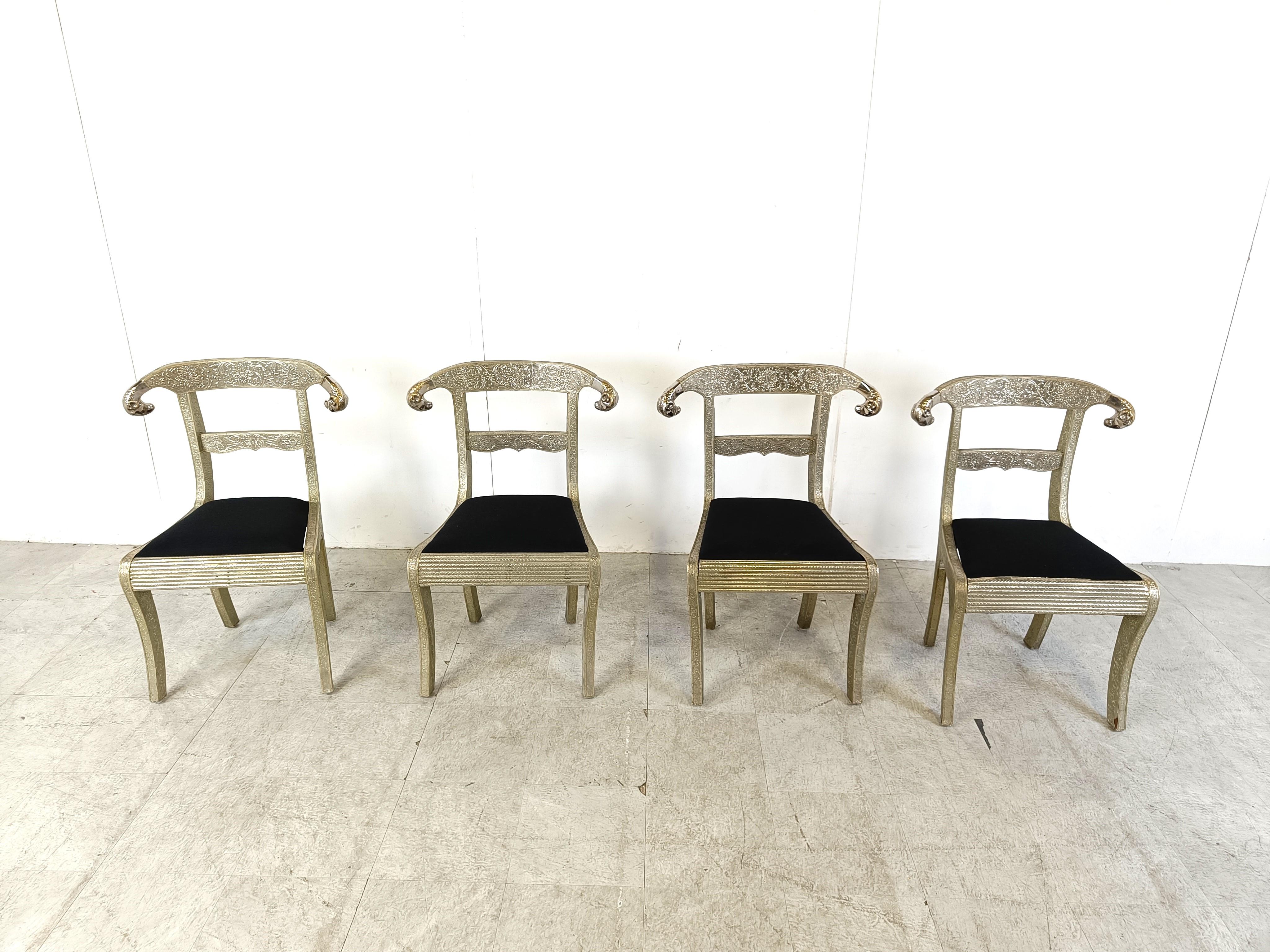 Set of 4 exquisite Anglo-Indian chairs.

These remarkable chairs are also known as an Indian Wedding Dowry Chairs.

They consist of a wooden frame covered with decorated silvered metal and two ram heads.

Newly upholstered in black fabric.

Such
