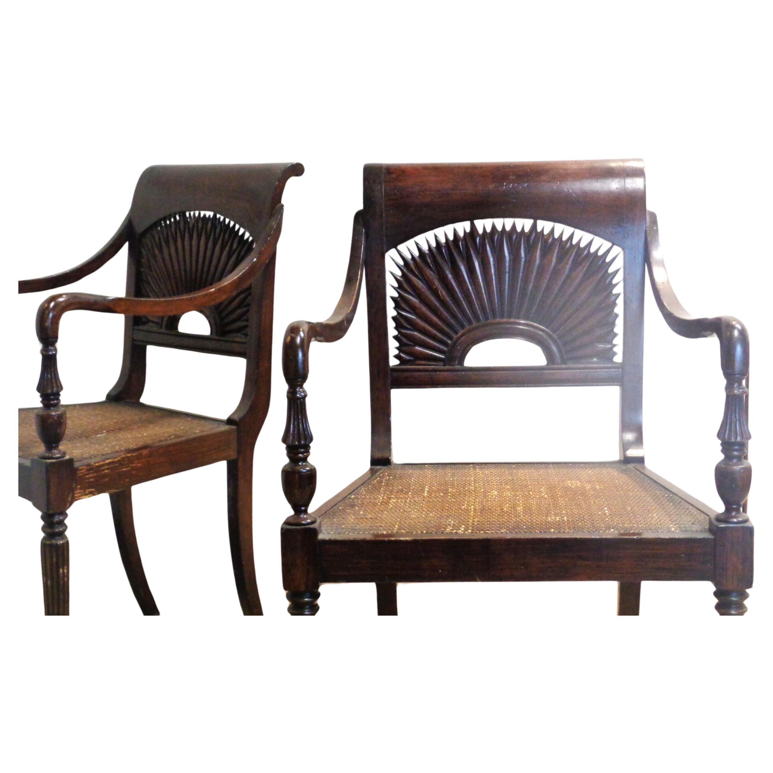 A pair of Anglo Indian style armchairs in a faux grained rosewood like finish w/ beautifully detailed carved sunburst backs / finely reeded legs / swooping curved arms / original tightly woven press cane seats / overall nicely aged rich surface