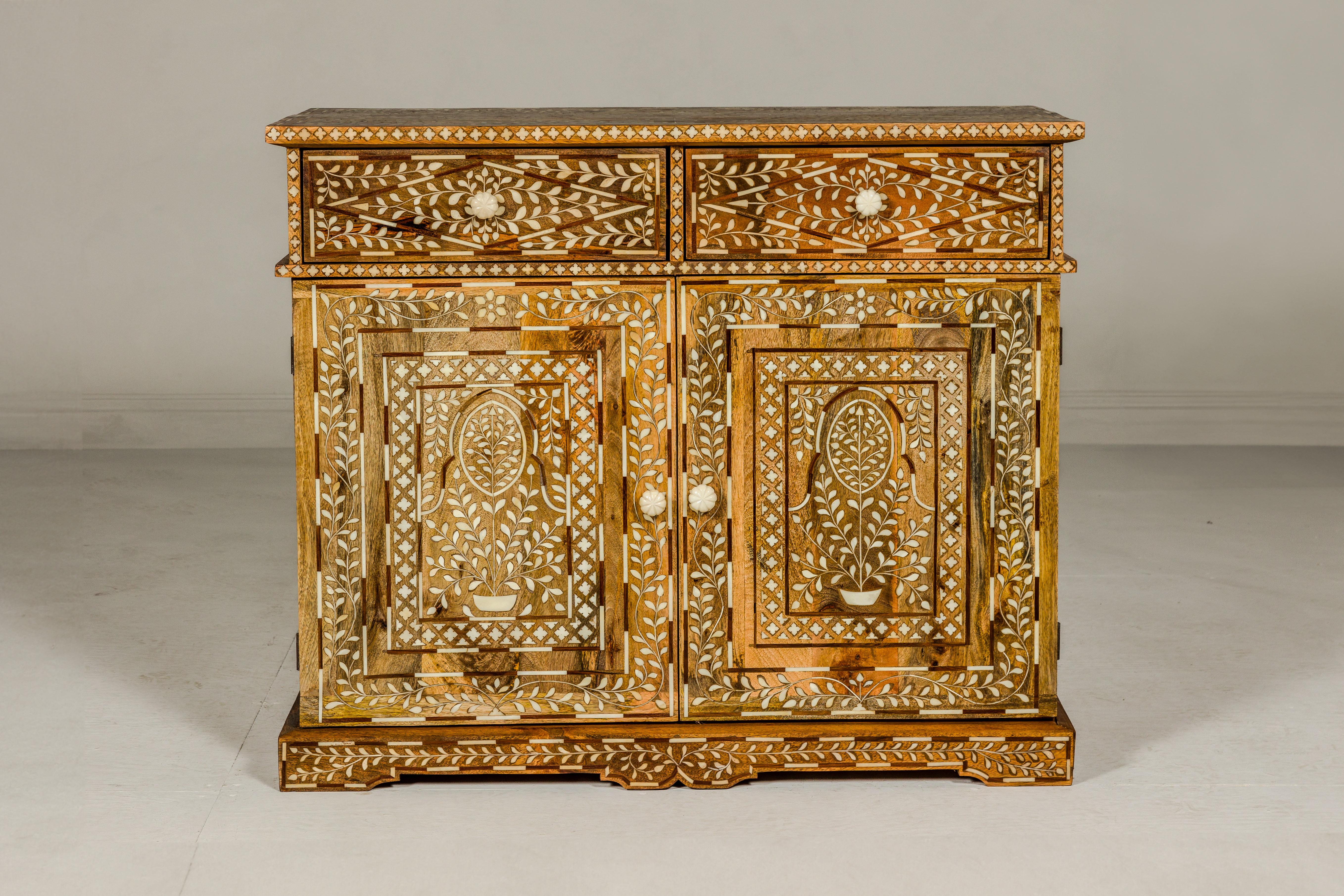 An Anglo-Indian style mango wood buffet with bone inlay décor, two drawers over two doors and bone hardware. Discover the enchanting allure of this Anglo-Indian style mango wood buffet, a captivating piece that gracefully melds functionality with