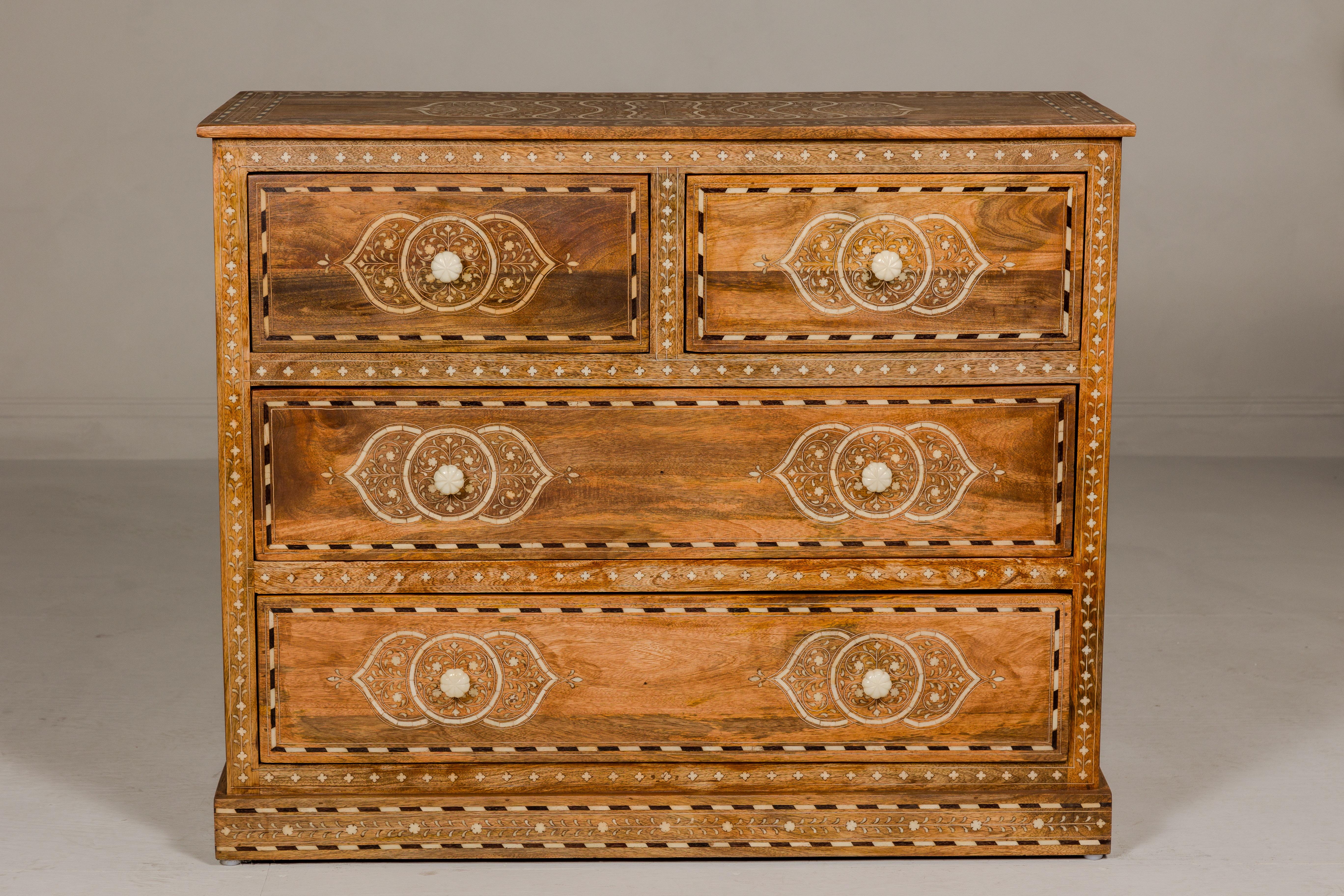 An Anglo Indian style mango wood chest with four drawers, floral themed bone inlay and bone hardware. Discover the elegance and craftsmanship of this Anglo-Indian style mango wood chest, a true masterpiece adorned with intricate floral-themed bone