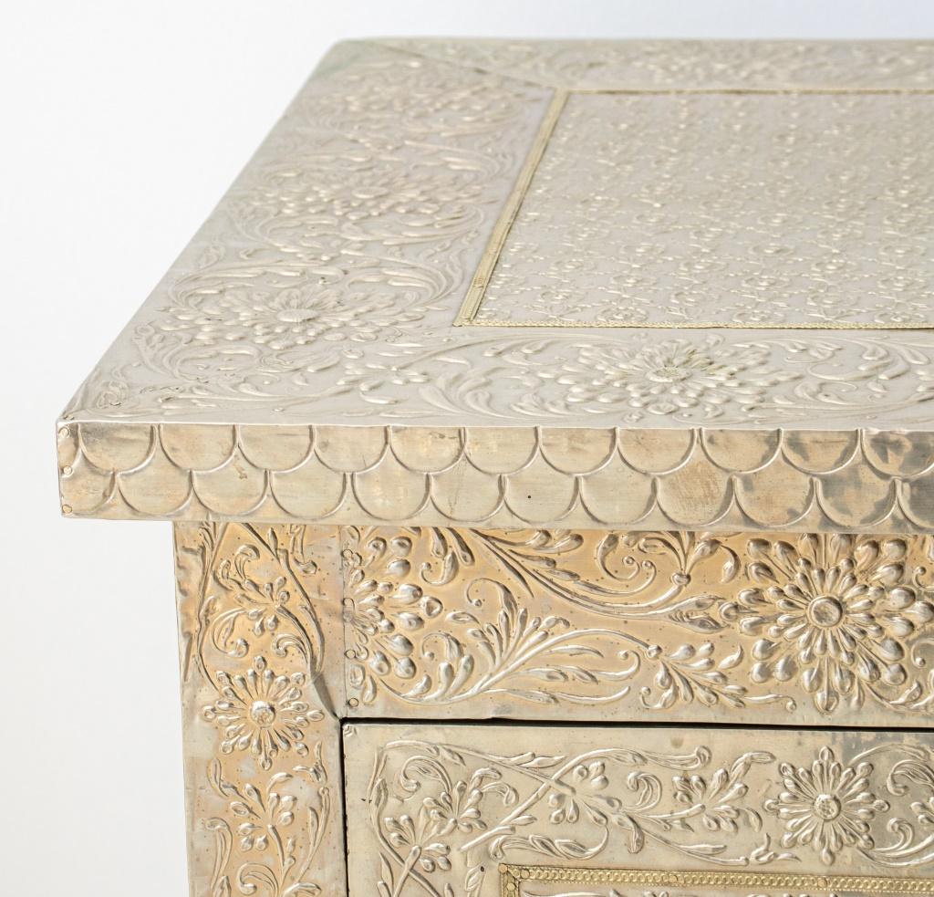 Anglo-Indian Style hammered silver-clad two-drawer commode, the rectangular top front and sides, completely veneered in repousse silver tone metal, the two drawers with crystal pulls, on square, tapering legs. 32