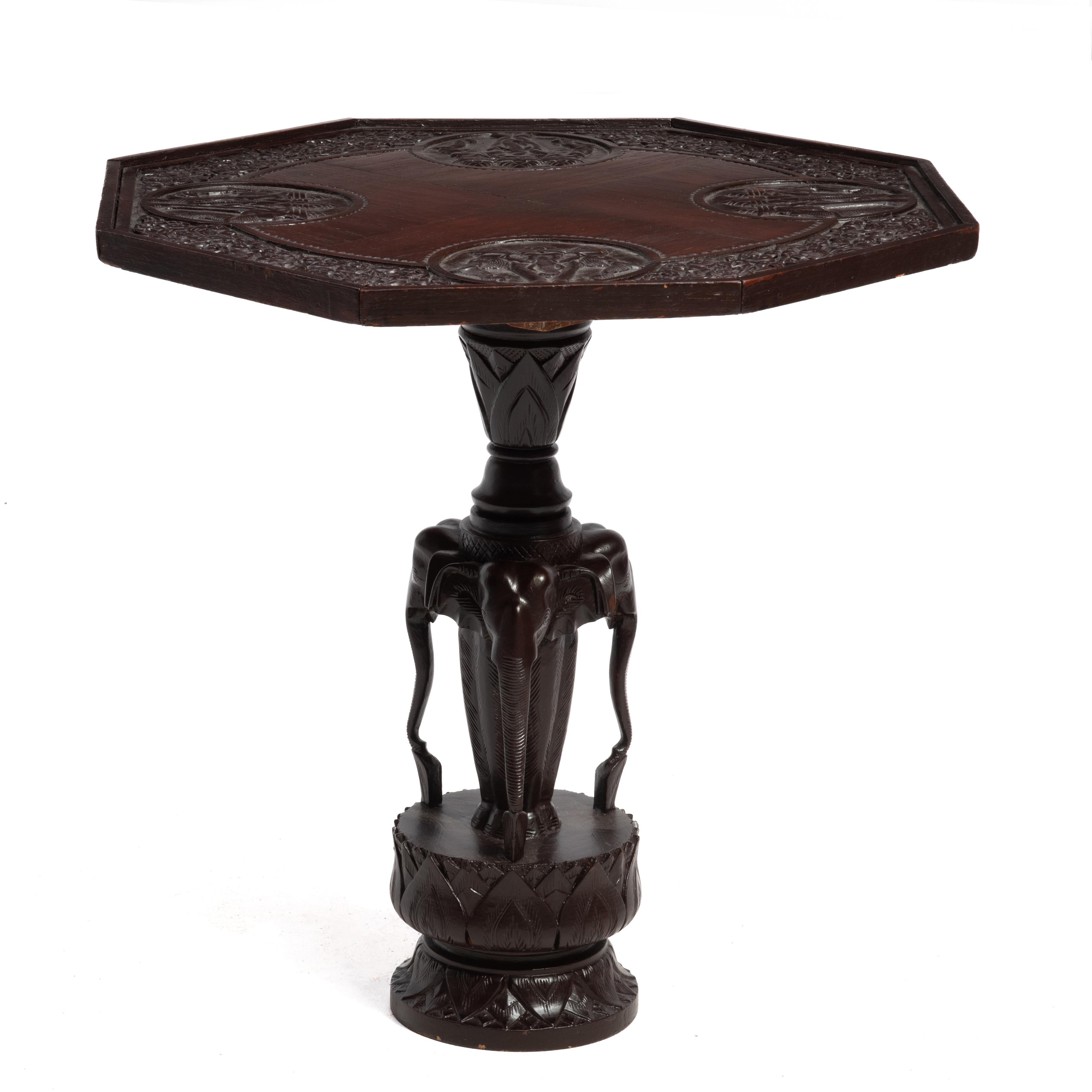 Lampe ou table d'appoint anglo-indienne vintage du milieu du 20e siècle. La table présente quatre panneaux sculptés en relief assortis à la forme octogonale.  et trois éléphants assortis sur une base de lotus. La base est sculptée dans une seule