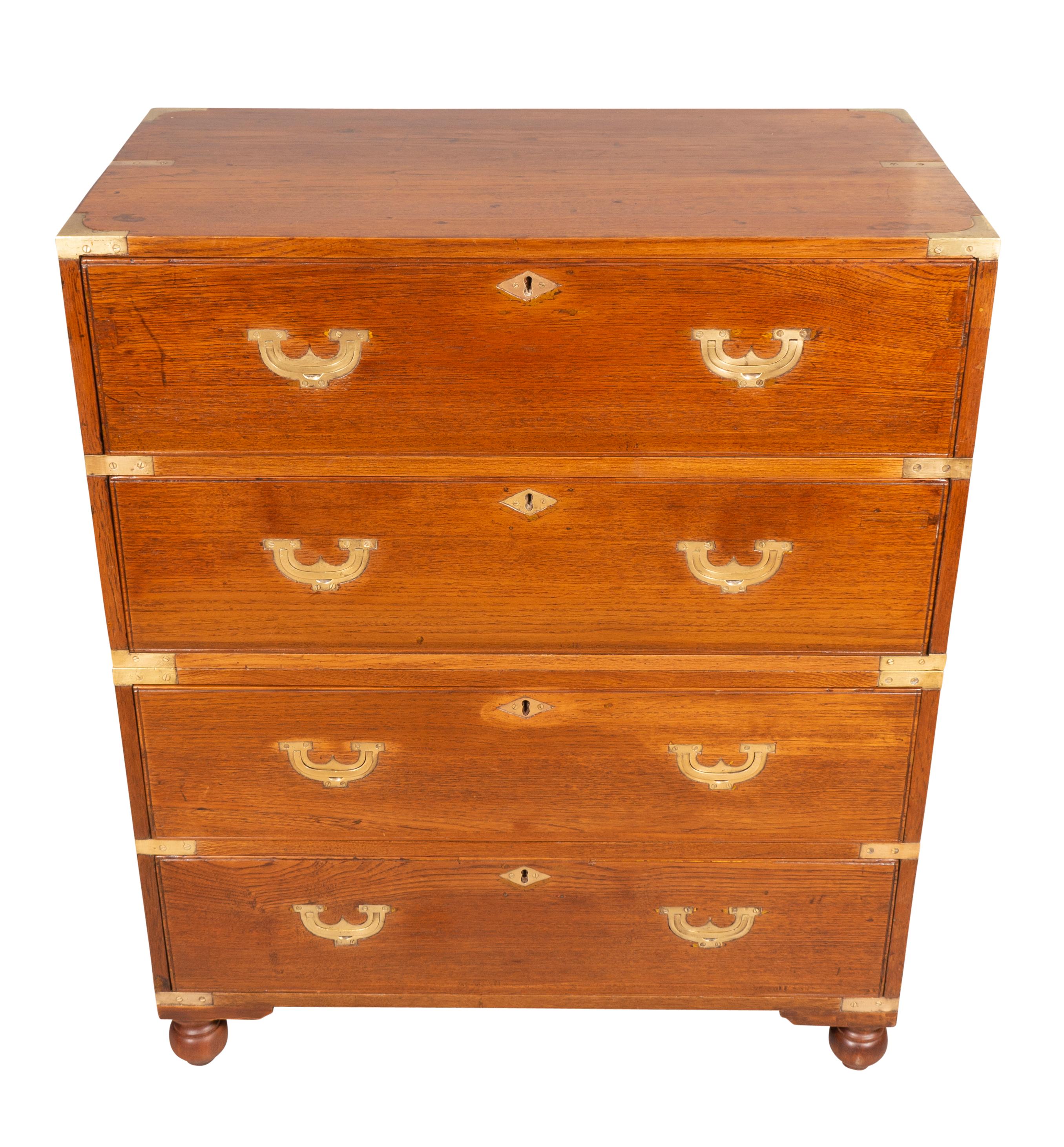 In two sections with a rectangular top over two long drawers over two long drawers. All with recessed brass handles. Iron side carrying handles. Ball feet.
