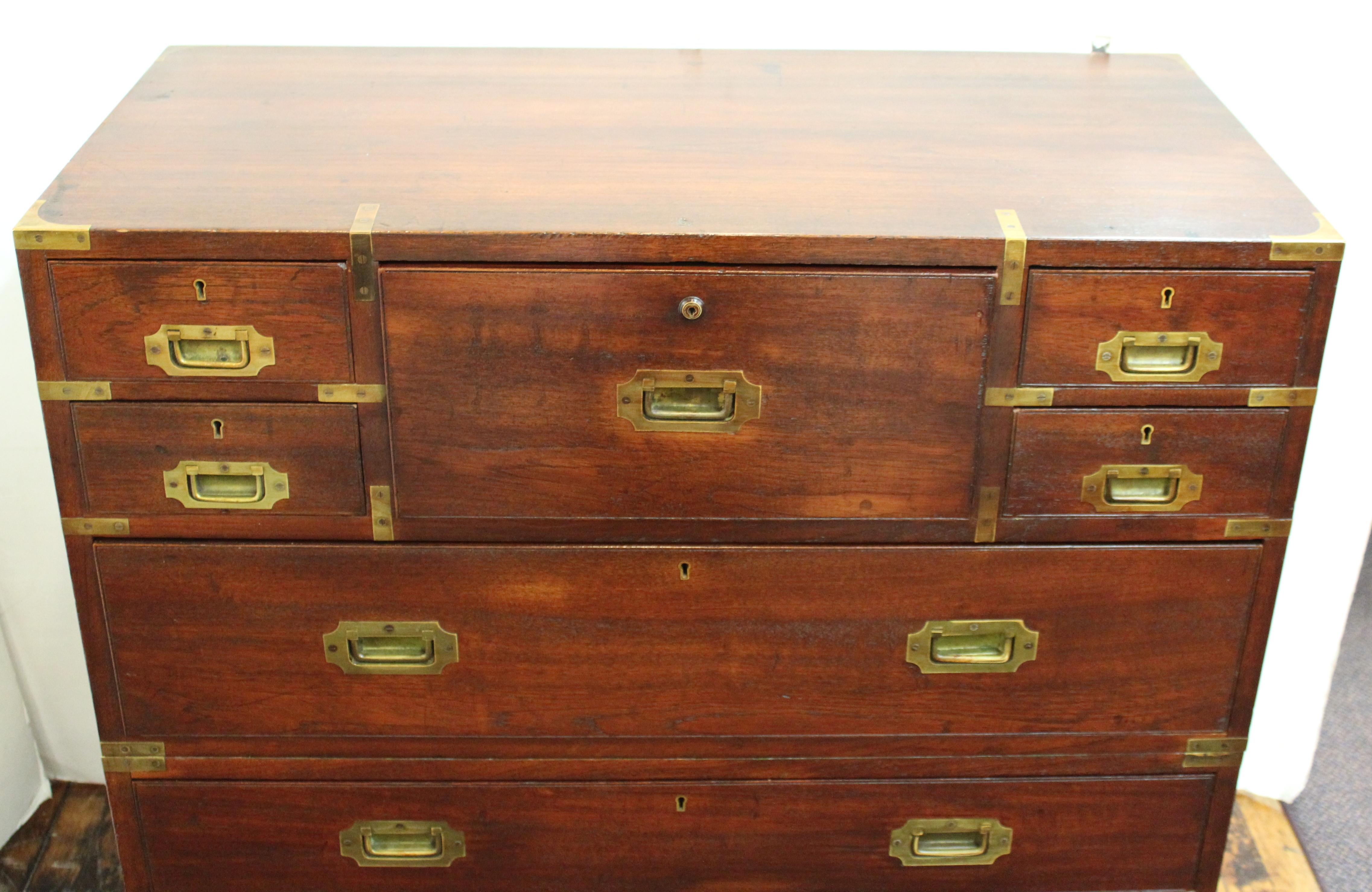 Victorian period Anglo-Indian Campaign chest in two parts, with brass mounts and hardware. The top central drawer contains a drop-front desk surface with multiple small drawers and a secret compartment. The lock plate on the desk drawer is stamped