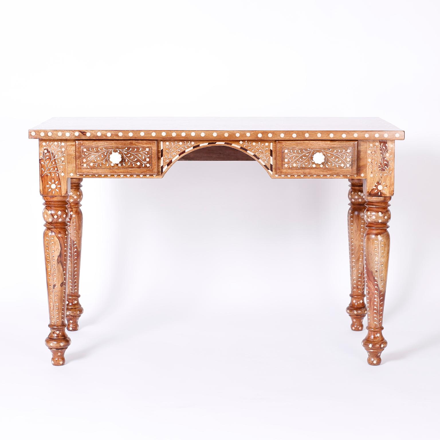 Anglo Indian two-drawer writing desk with symbolic inlays of bone and ebony. The dramatic top has a center medallion and emanating floral motifs, the turned legs feature exotic wood grains.