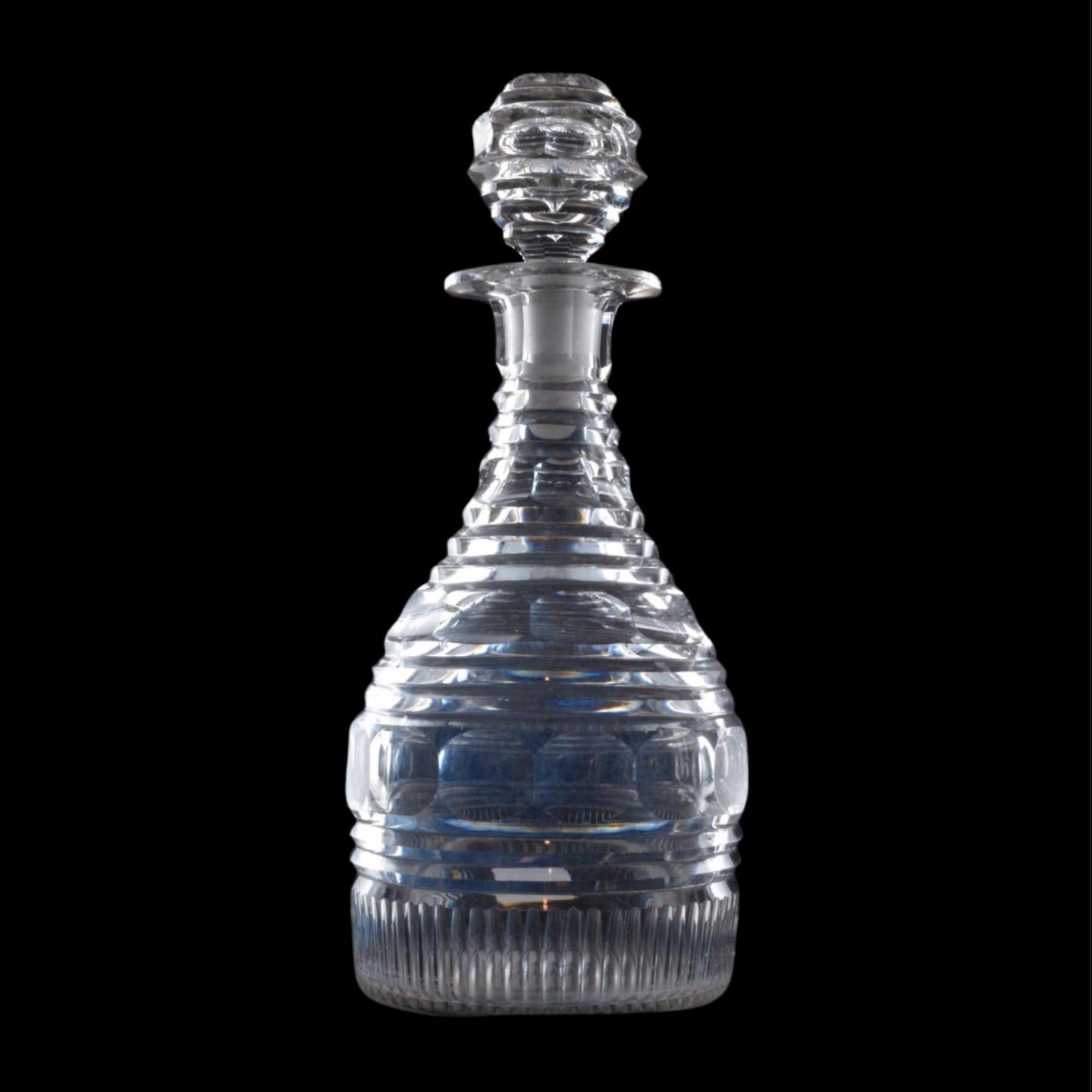 A fine and useful decanter, Prussian shape, of blown glass with prism cutting typical of the period; along with fluting and lens cutting. There can be no doubt this is the original stopper.
