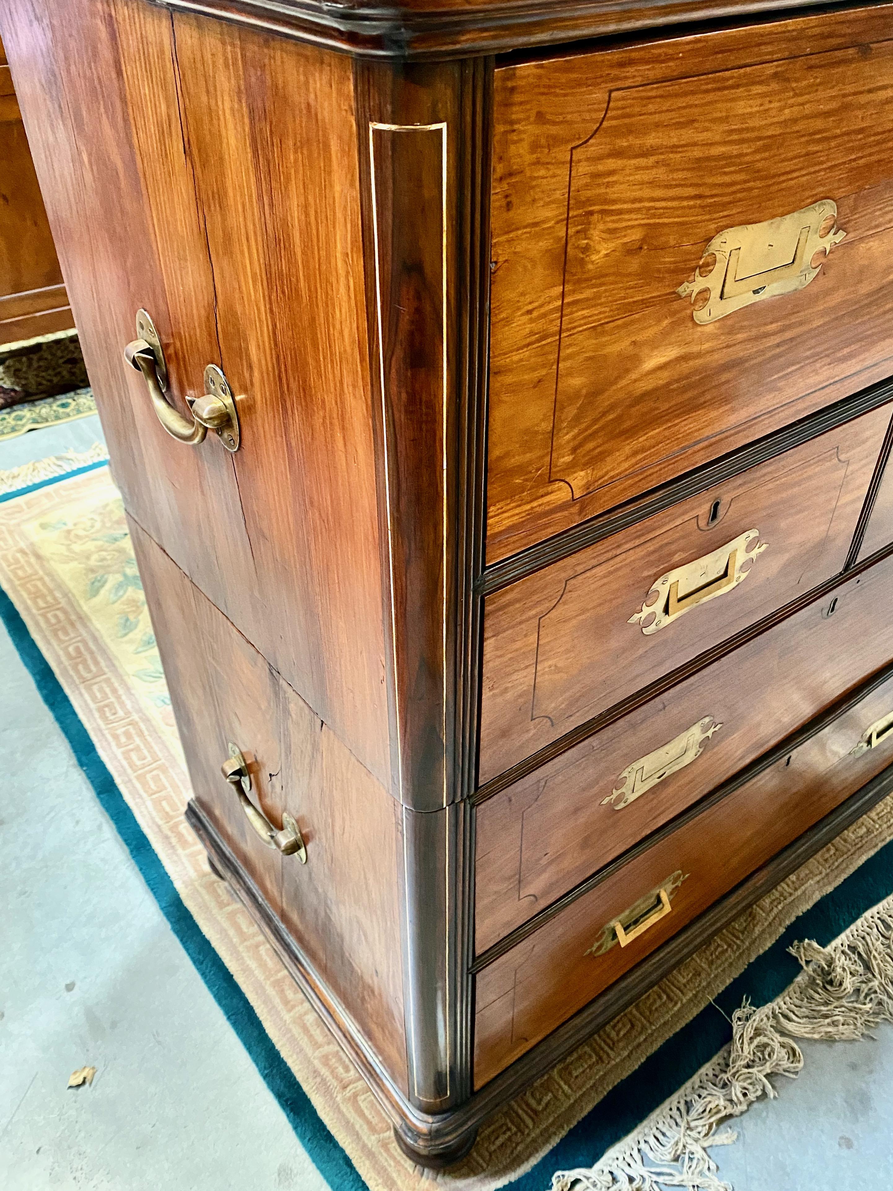This is a unusual style of 19th century Anglo-Indian or Raj campaign chest in teak and other fine woods with detail line inlay. The two part chest is in overall very good condition. The fitted Secretaire section's arrangement of the drawers, locked