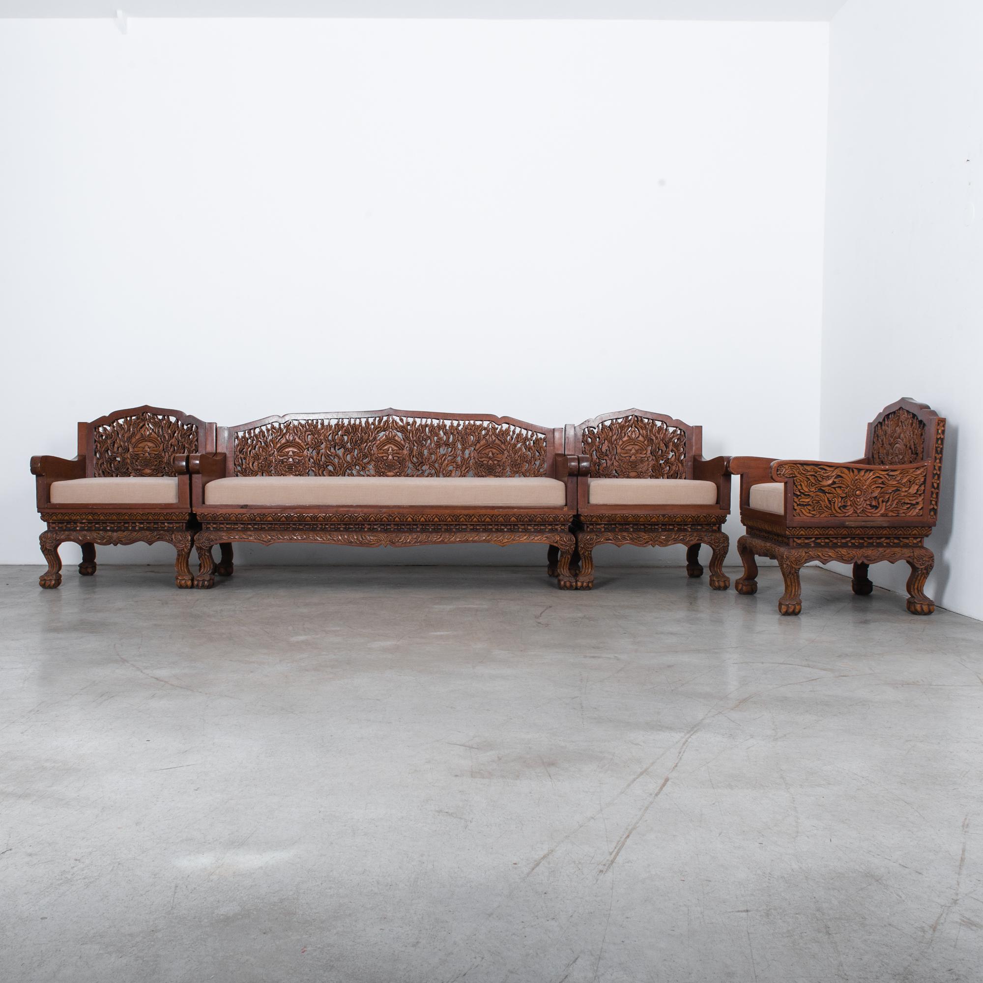 Intricately carved sofa set found in an orientalist style Belgian carriage house. From circa 1920s Southeast Asia, carved from dense rosewood and re-upholstered in warm cream fabric. This amazing set features stunning graphic relief of dragons face