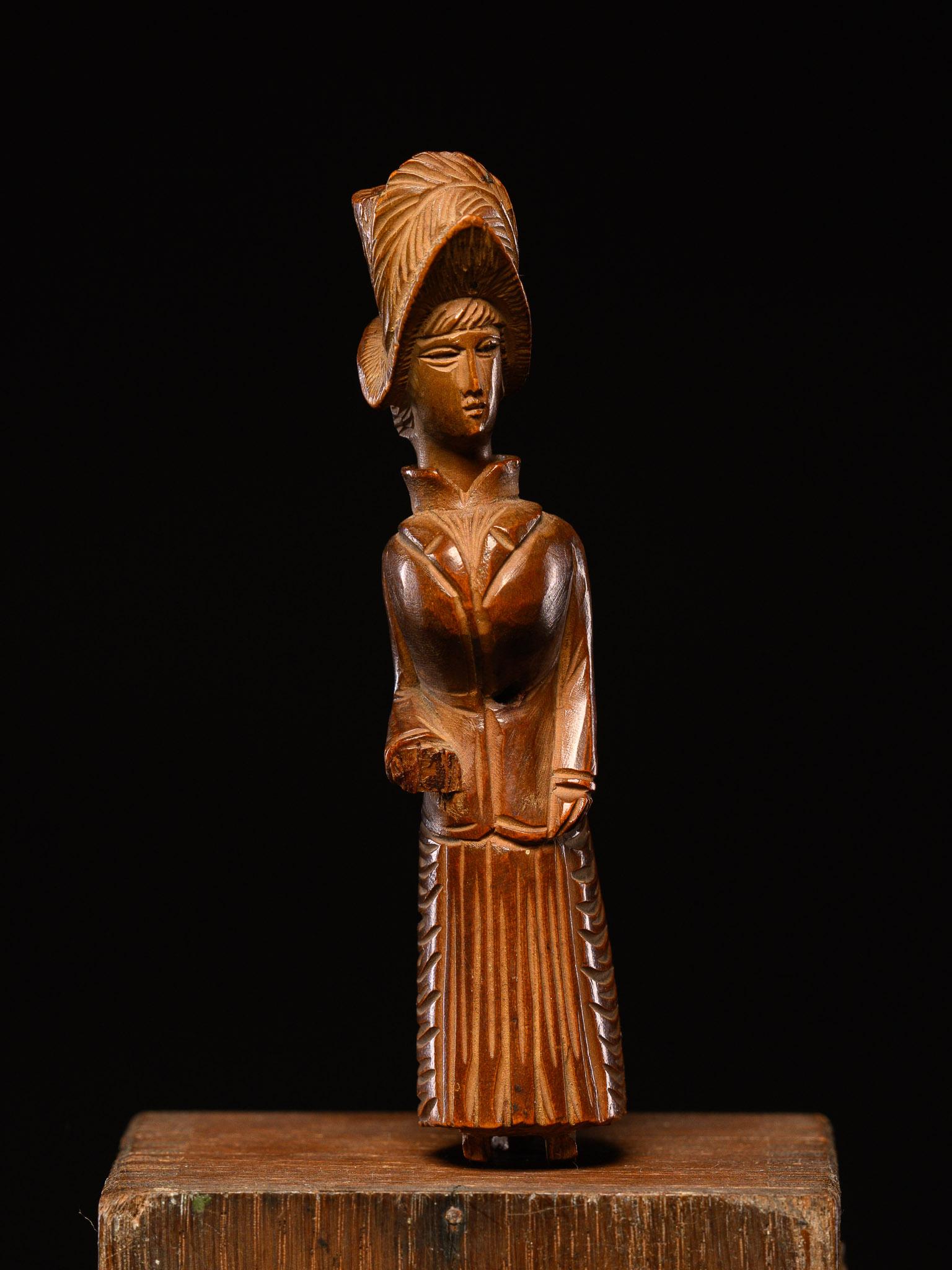 A snuff container shaped as a European woman in 19th-century attire, with a unique design—a small black baby figure slides under her skirt.