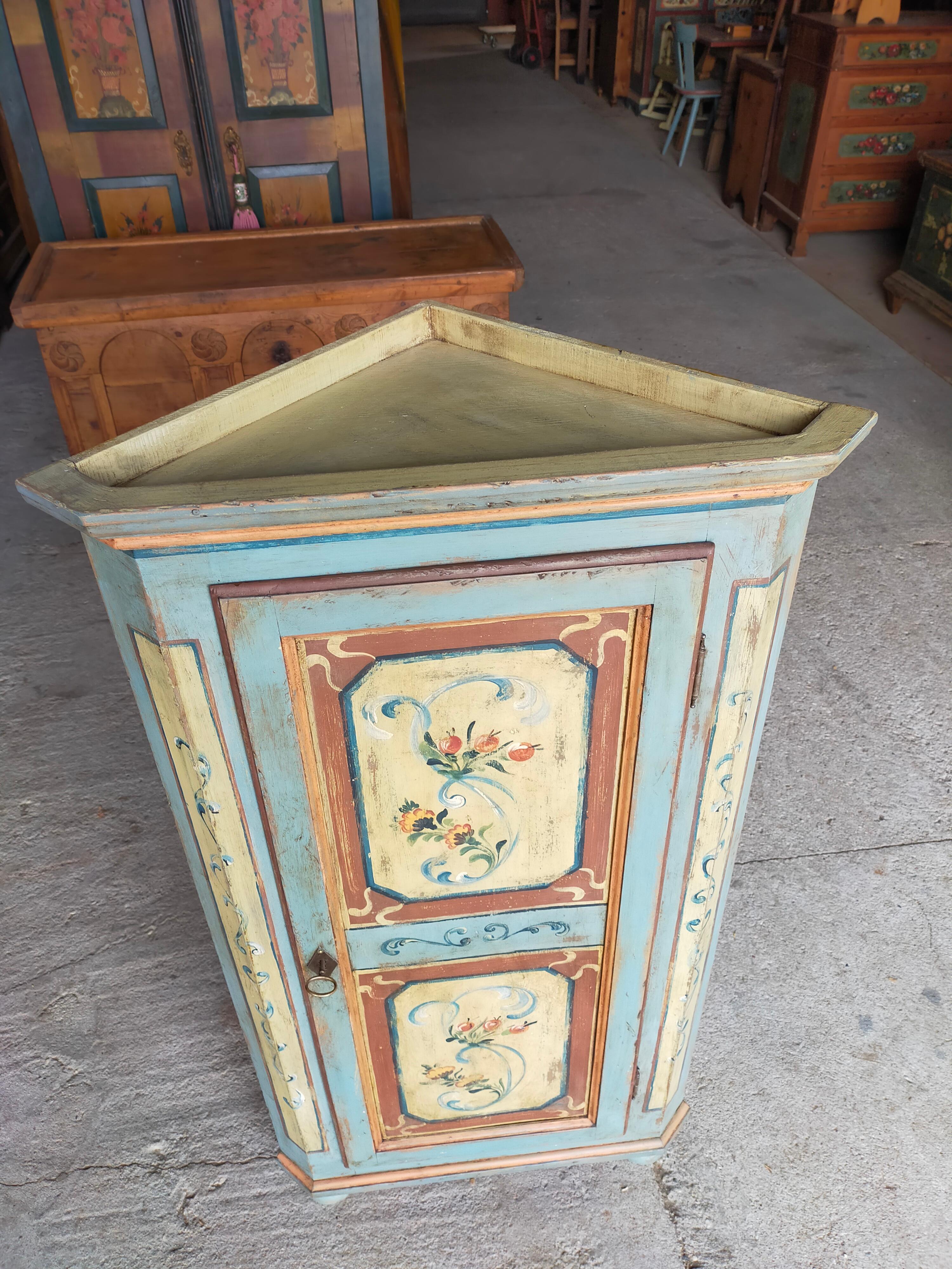 Spruce corner cabinet from the early 1900s. 
With two interior shelves.
Door painted with floral motifs, with secret visible in photo.

Other photos or information at customer's request.