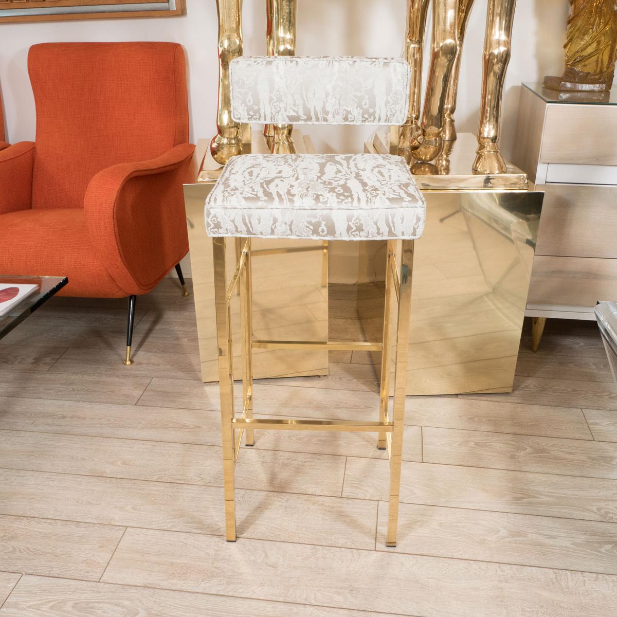 Angular brass bar stool with upholstered seat and back.