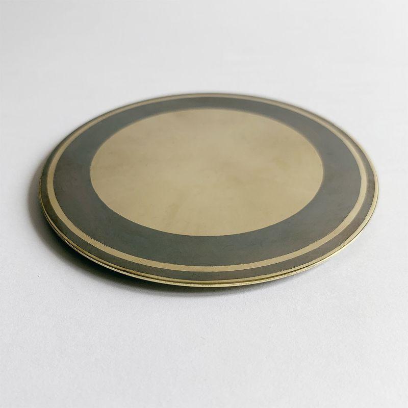 A dynamic contrast of azure and beige veiled by delicate, unpredictable shades resulting from the use of chemical oxides defines this contemporary-style set of six brass coasters. The concentric decoration owes its artistic signature to the