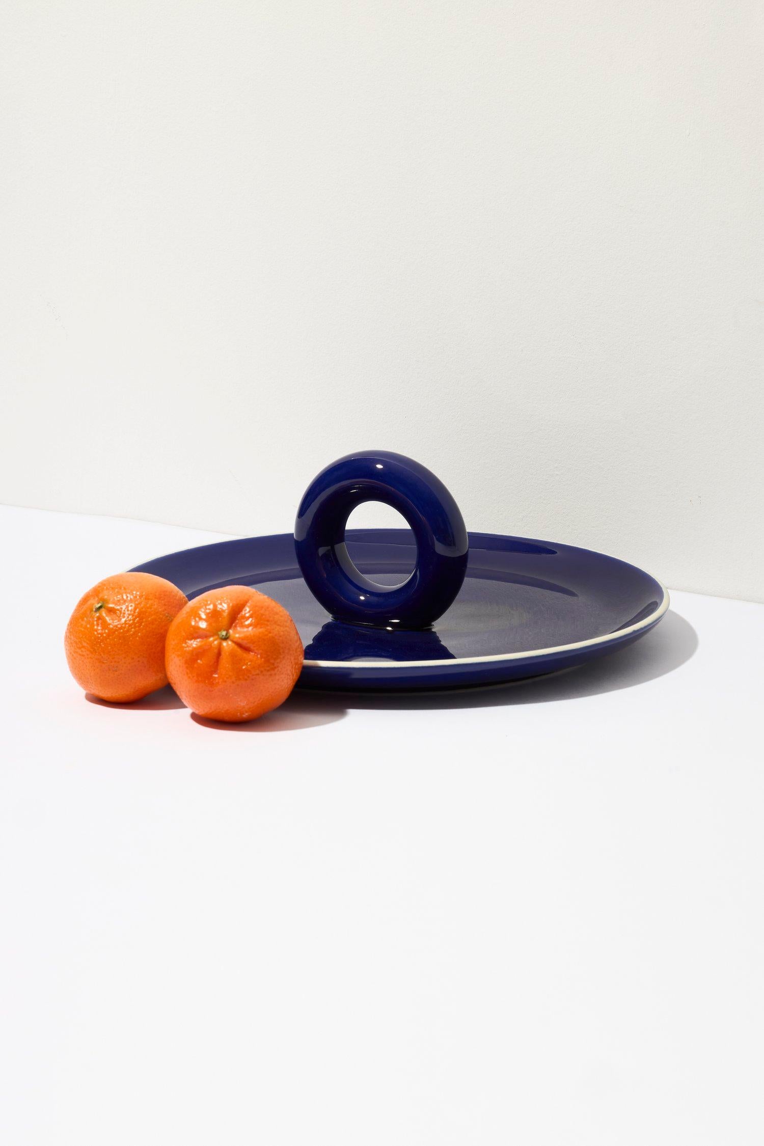 ANIELA can be described in three words: perfect-fruit-plate! Of course, it works just as well for serving sweets or savory snacks. Its wide base and a funny pretzel-shaped handle gain a distinctive character thanks to the intense glaze color. The