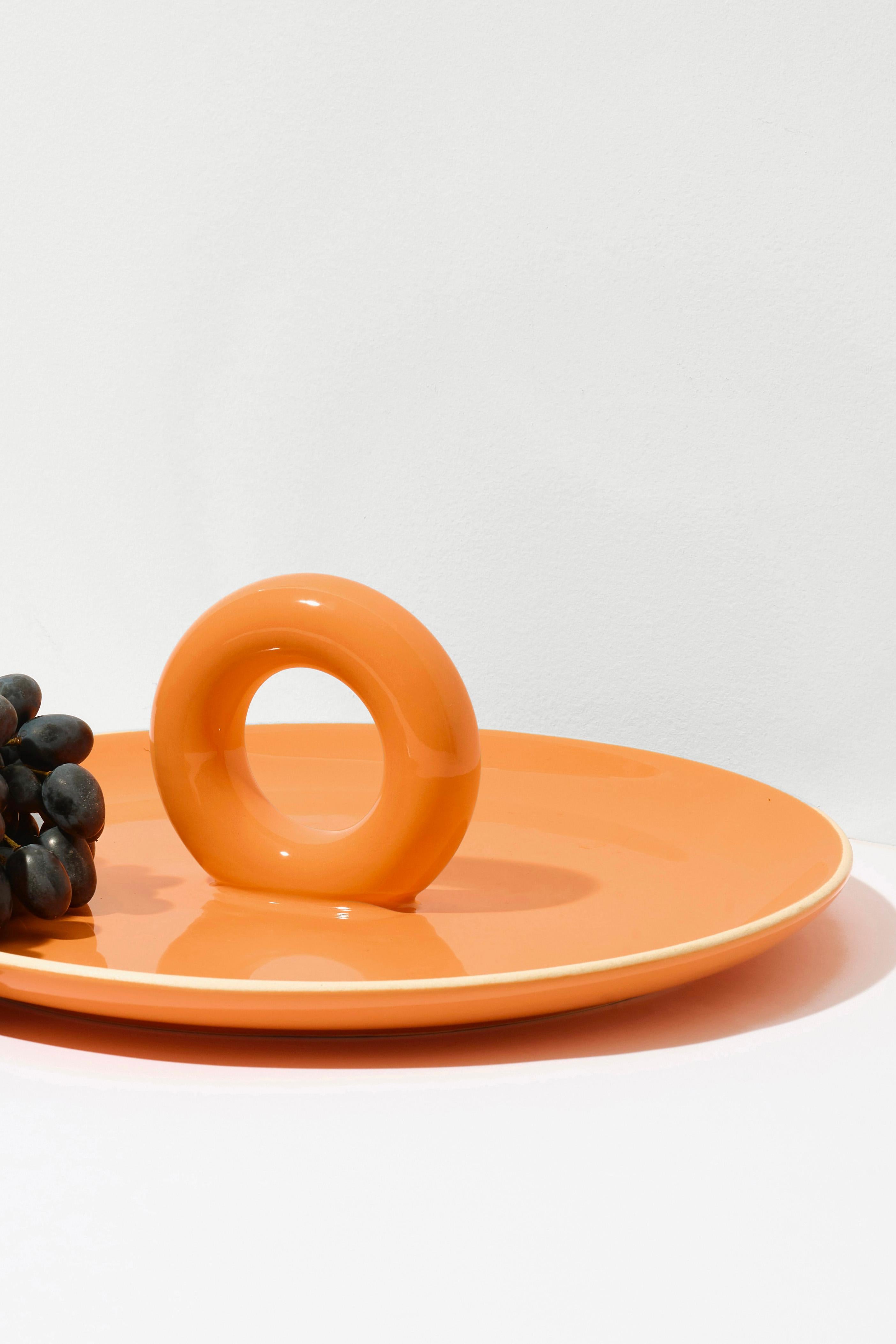 ANIELA can be described in three words: perfect-fruit-plate! Of course, it works just as well for serving sweets or savory snacks. Its wide base and a funny pretzel-shaped handle gain a distinctive character thanks to the intense glaze color. The