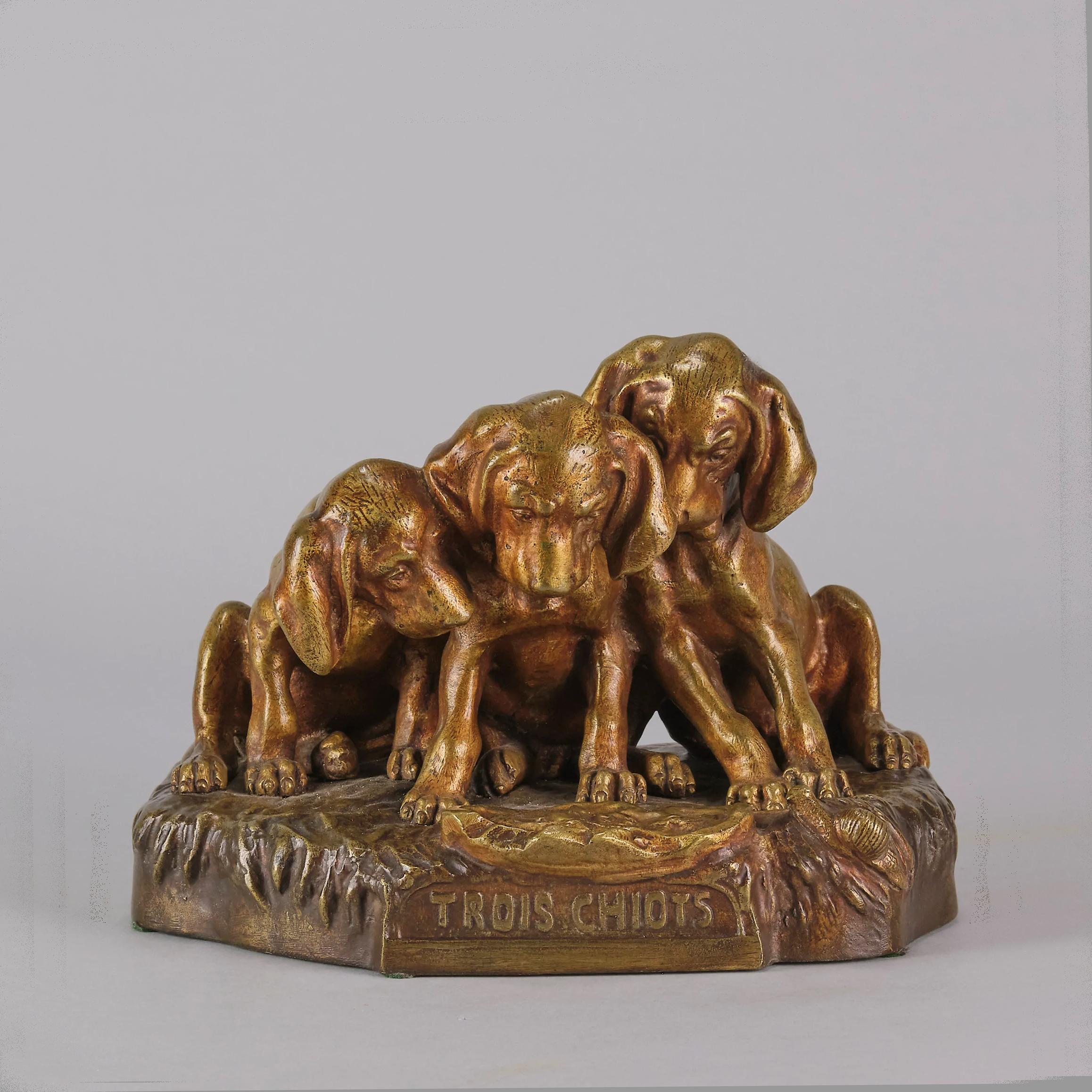 A charming early 20th century animalier gilt bronze group of three seated puppies fascinated by an approaching snail. The bronze with fine hand chased surface detail and good colour, raised on a shaped marble base and signed George