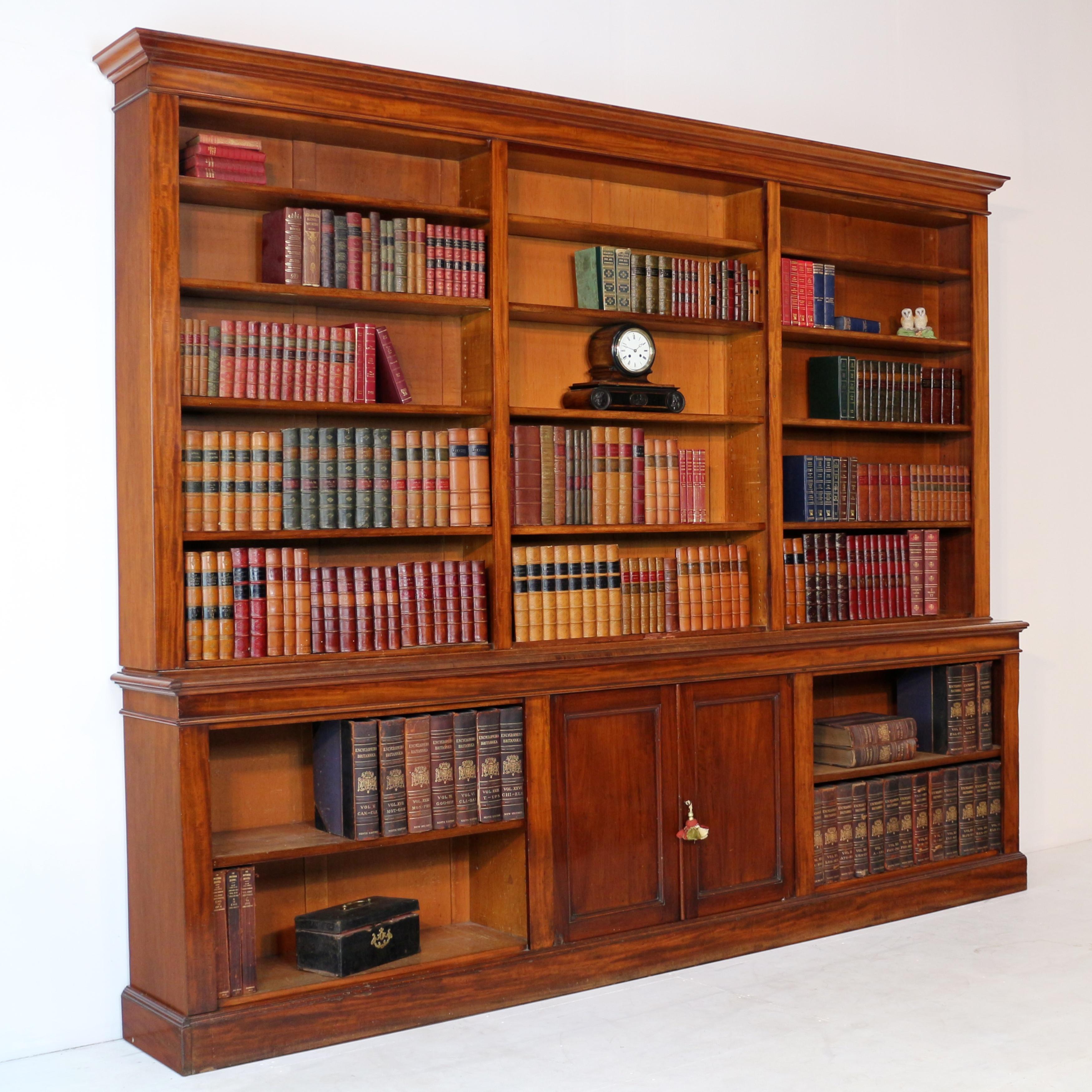 A handsome William IV/early Victorian mahogany open library bookcase. With a square cornered moulded cornice above three open shelved sections each with four adjustable shelves, the stepped out base with a central pair of fielded panelled doors and