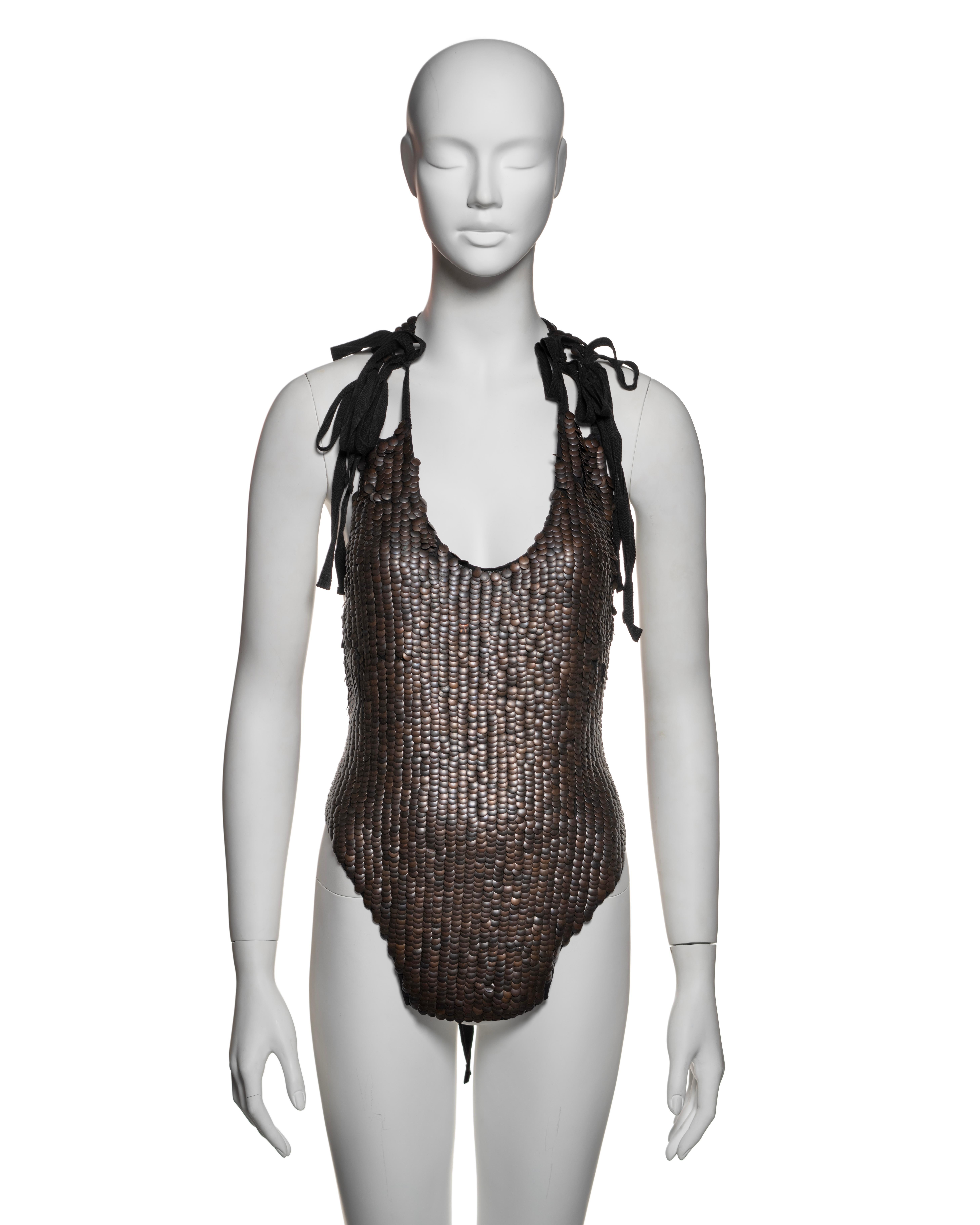 This rare artisanal Ann Demeulemeester top features an intricate construction of bronze-tone metal discs arranged in a scaled pattern across the bodice. The discs form a textured, almost armour-like surface, with the top fastening via black ribbon