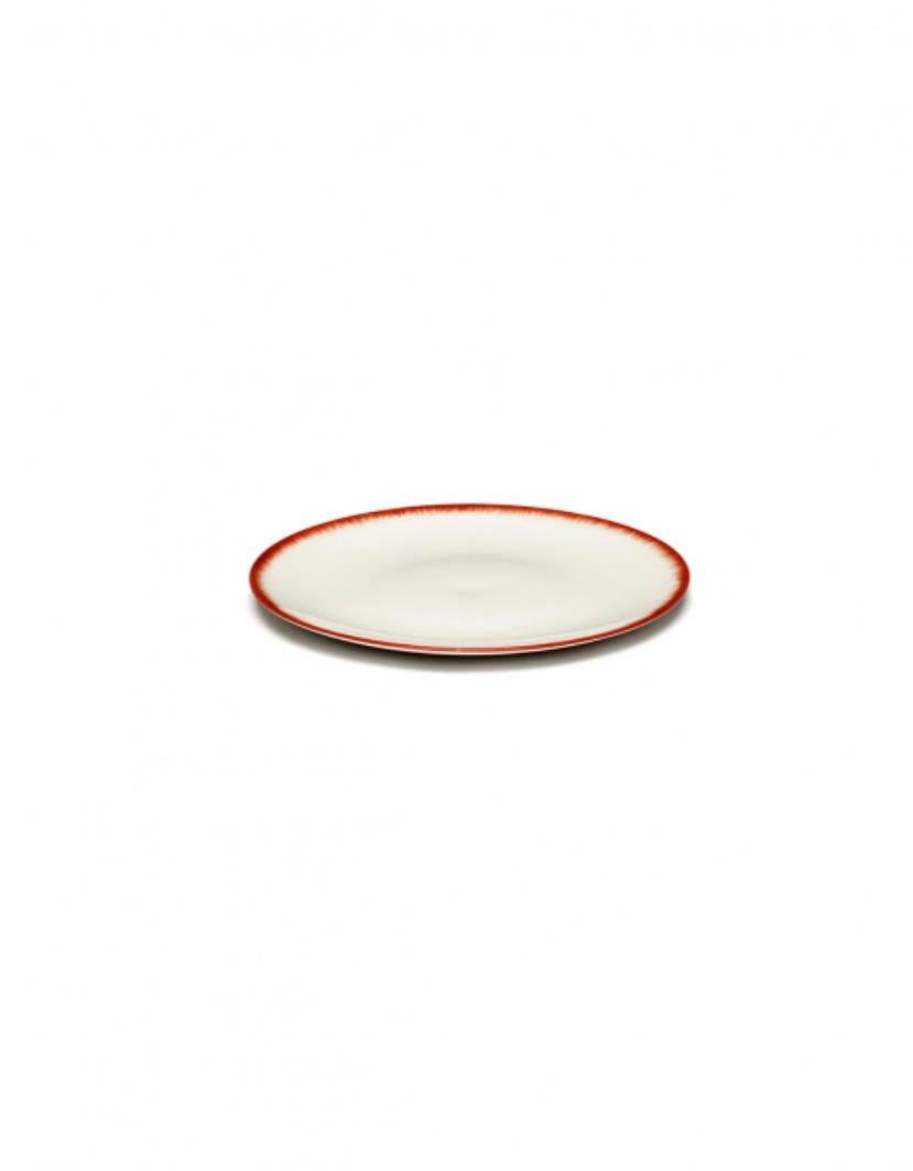 Ann Demeulemeester hand-painted porcelain 14 centimeter plates, in set of two. A red matte glaze on the outside with a glossy off-white glaze on the inside. The contrast between matte and glossy, but also the contrast of color, are typical of the