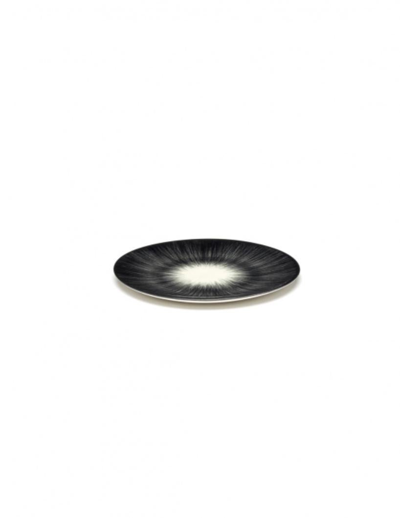 Set di due piatti in porcellana Ann Demeulemeester da 14 centimetri. Uno smalto nero opaco all'esterno e uno lucido bianco sporco all'interno. Il contrasto tra opaco e lucido, e anche quello tra nero e bianco sporco, sono tipici dello stile di Ann