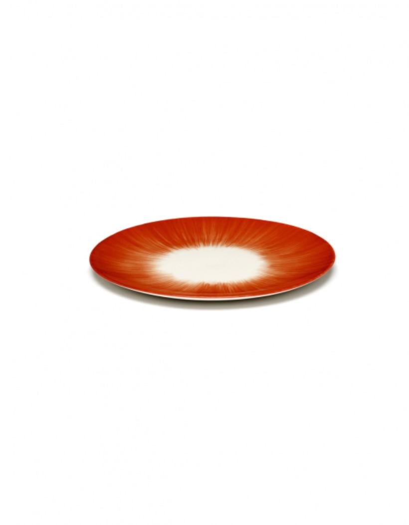 Zwei von Ann Demeulemeester handbemalte Porzellanteller mit 17,5 cm Durchmesser. Eine rote, matte Glasur auf der Außenseite und eine glänzende, cremefarbene Glasur auf der Innenseite. Der Kontrast zwischen matt und glänzend sowie der Farbkontrast