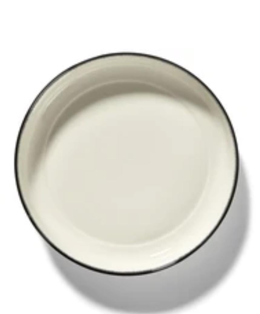 Set of two hand-painted 27-centimeter porcelain high plates from Ann Demeulemeester. The plates rest on a pedestal and literally elevate the food that is served on them. A black edge accents the glossy off-white glaze. The contrast between matte and