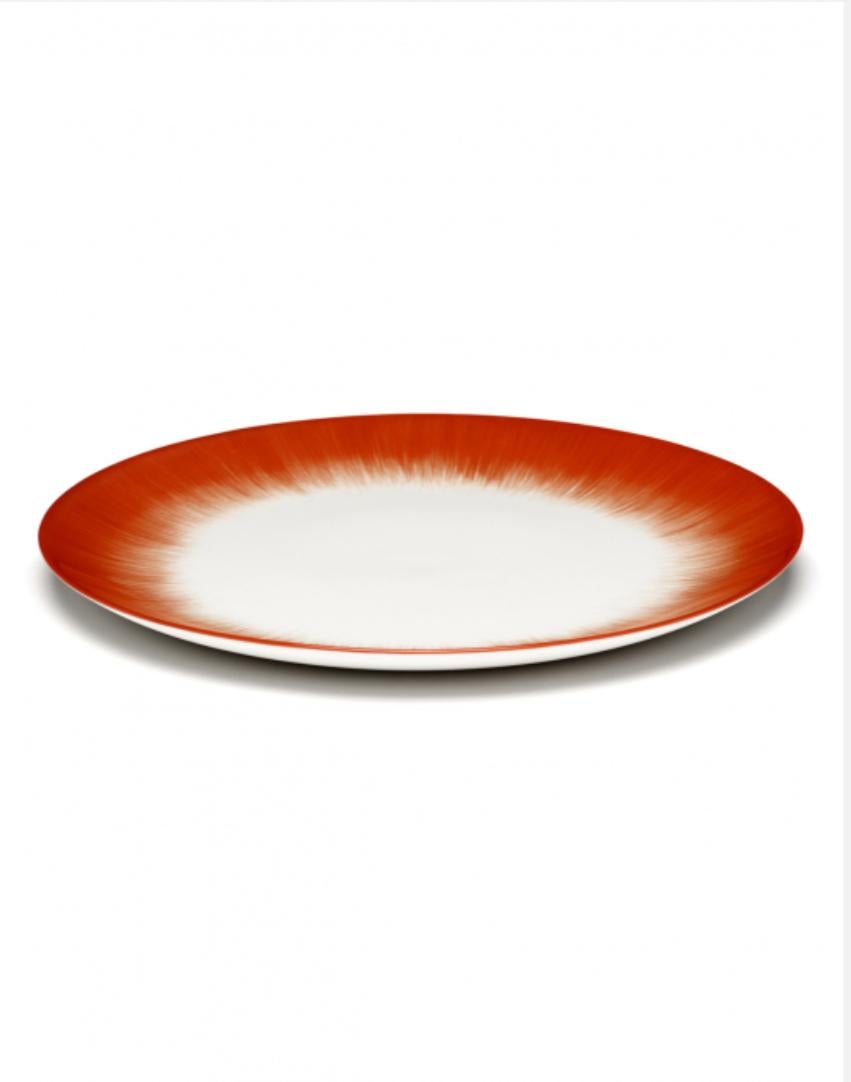 Set of two Ann Demeulemeester hand-painted, porcelain 28 centimeter plates. A red matte glaze on the outside with a glossy off-white glaze on the inside. The contrast between matte and glossy, but also the contrast between red and off-white, are